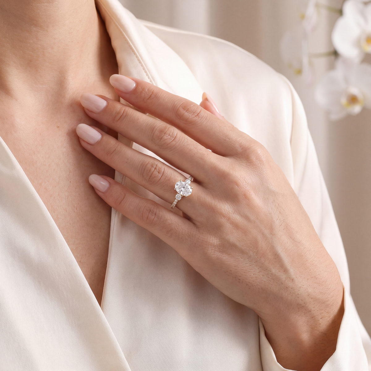 Model wearing the yellow gold oval moissanite engagement ring with hand resting on chest.