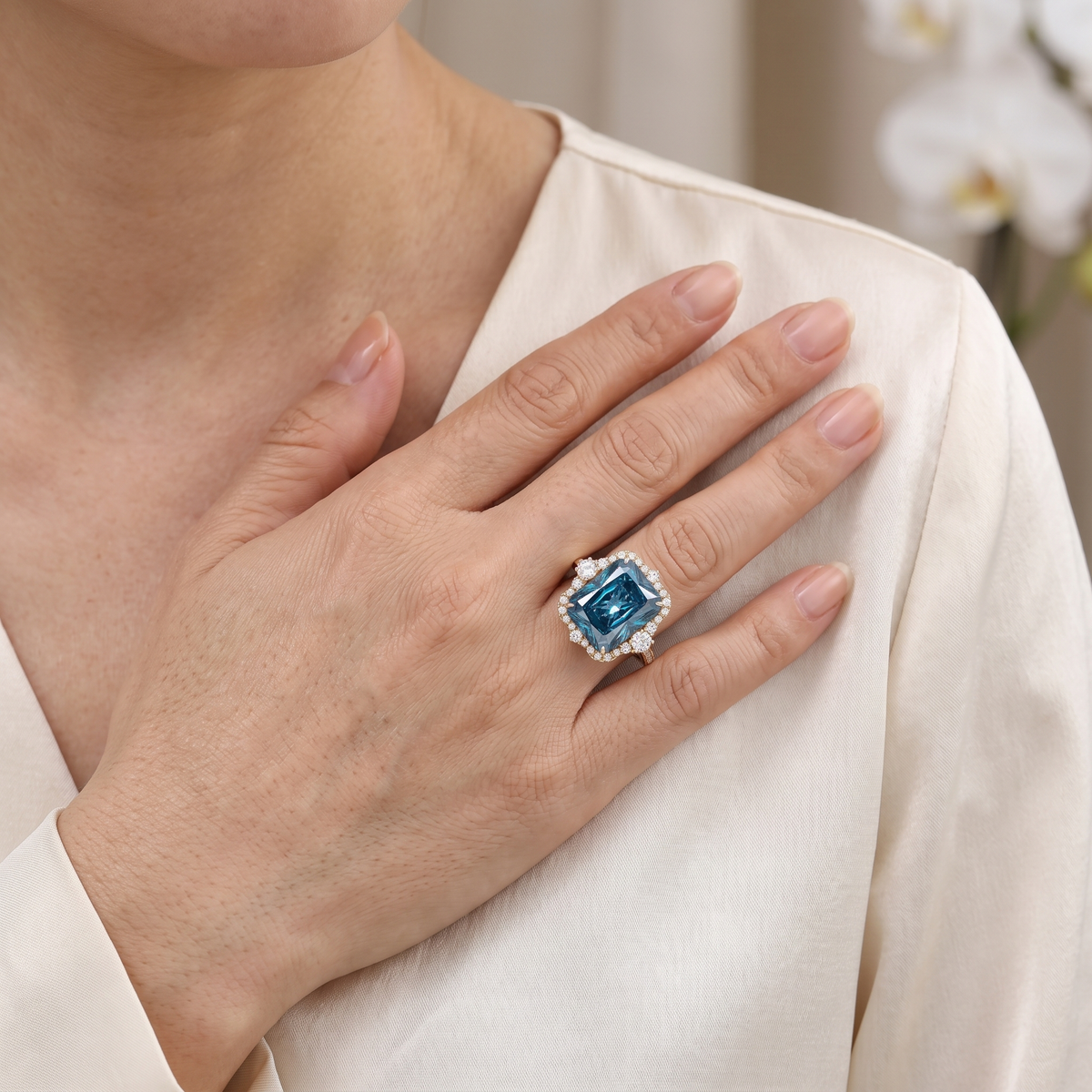 Radiant cut blue moissanite halo ring in rose gold showcased on a model's hand.