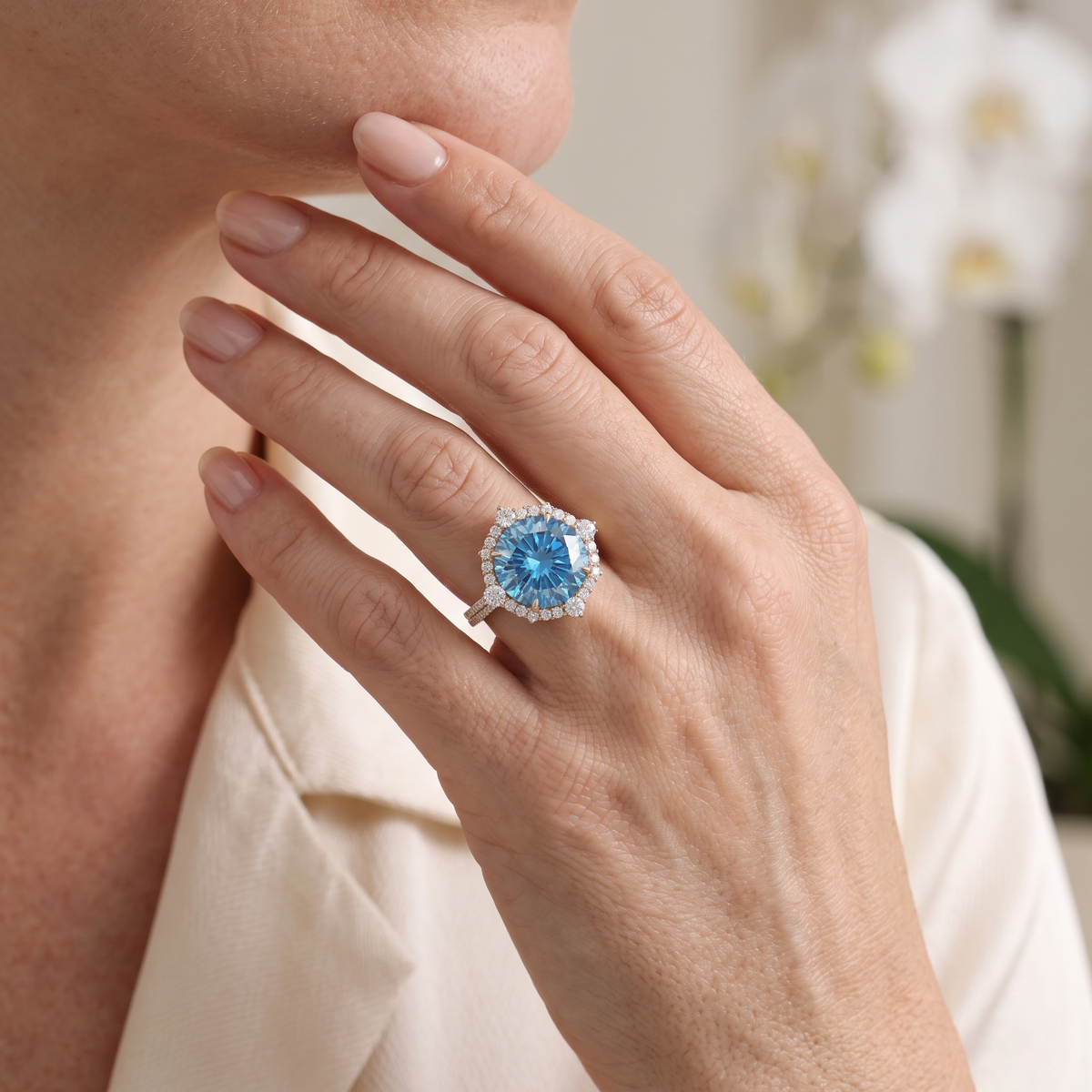 Model wearing a round blue moissanite halo ring in rose gold.