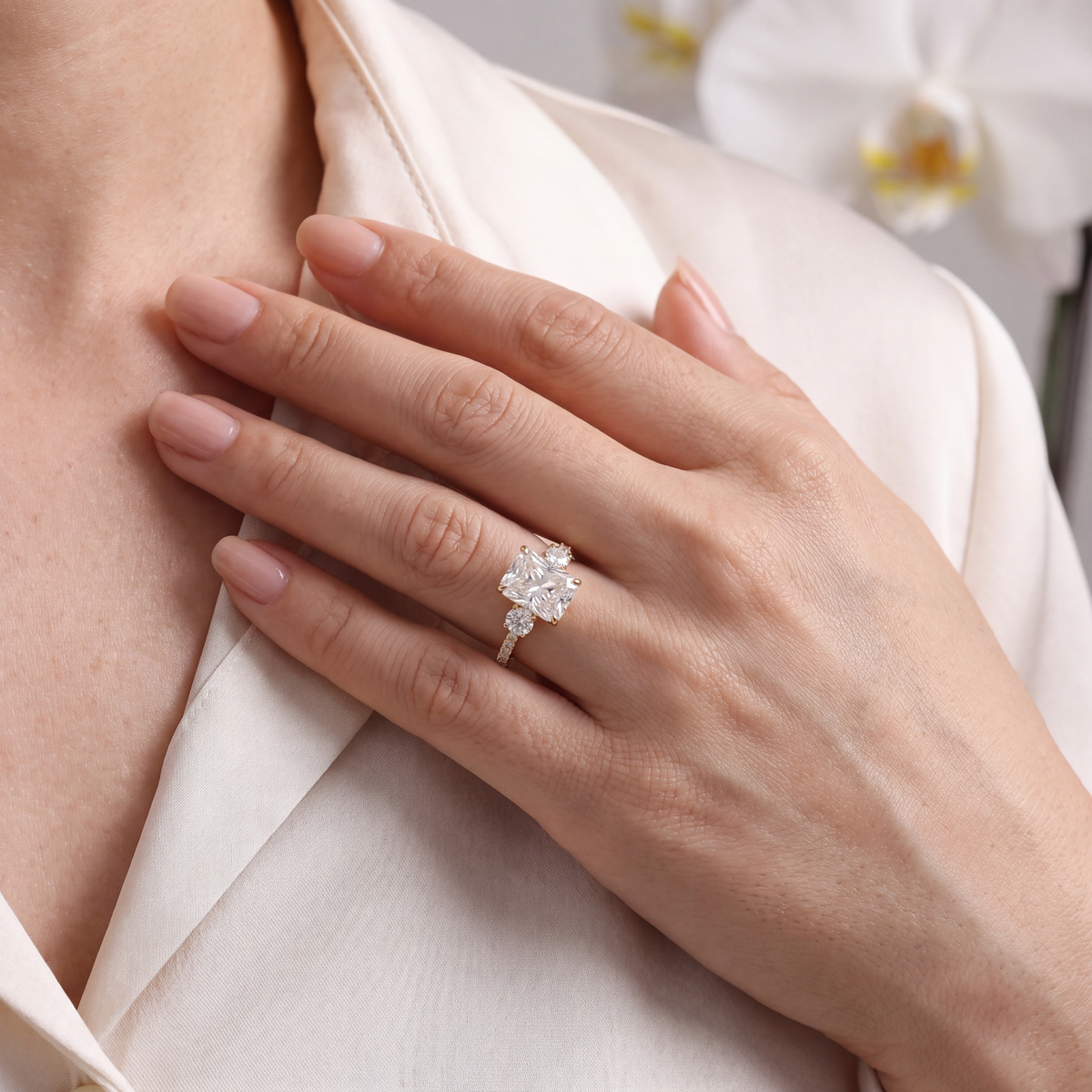 Model wearing a yellow gold radiant cut moissanite three-stone engagement ring.