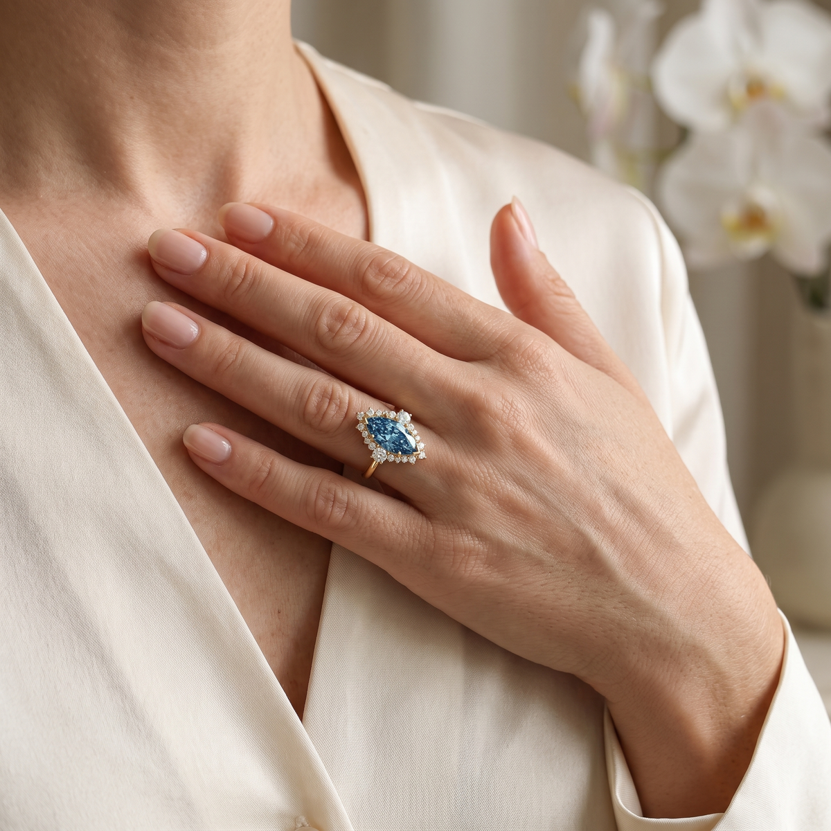 Marquise-cut blue moissanite halo ring in rose gold worn by a model in an elegant lifestyle portrait.