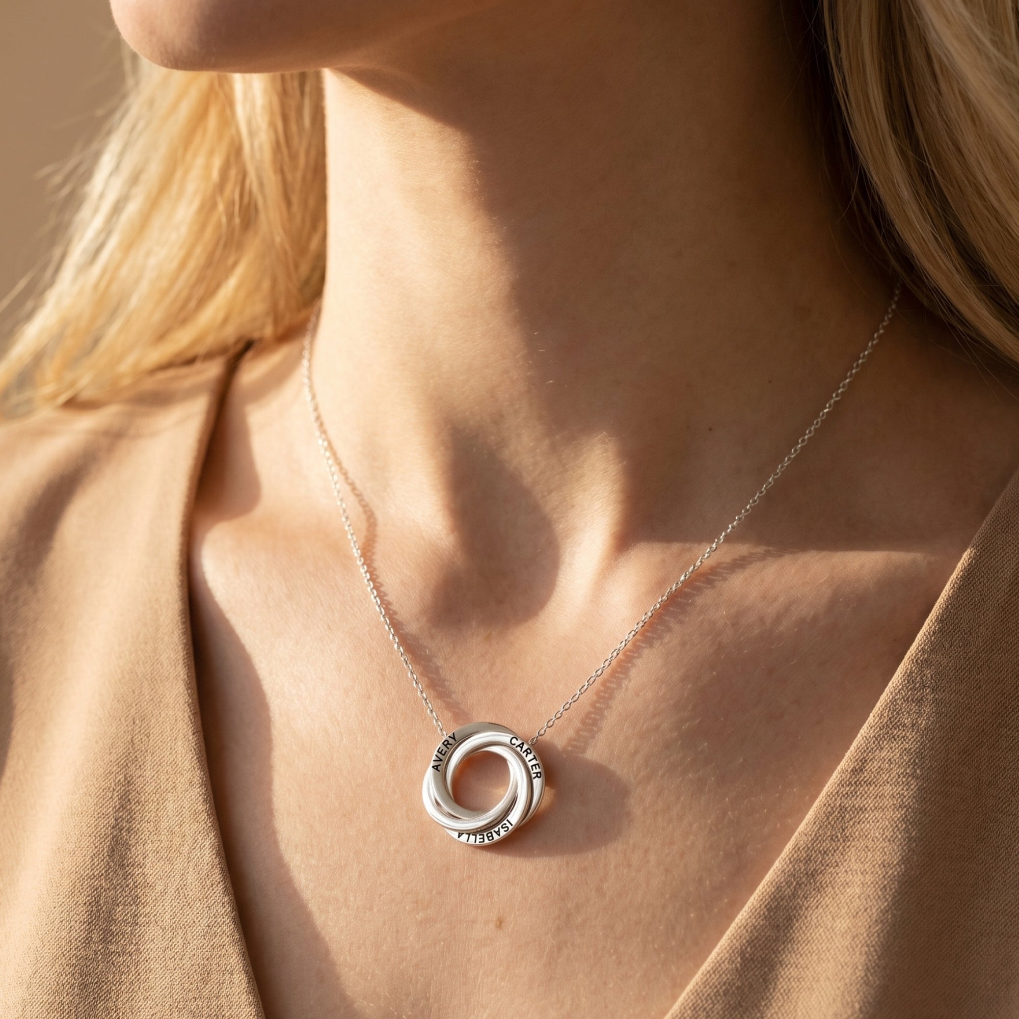 Silver Camilla necklace with three interlocked engraved rings worn by a model.
