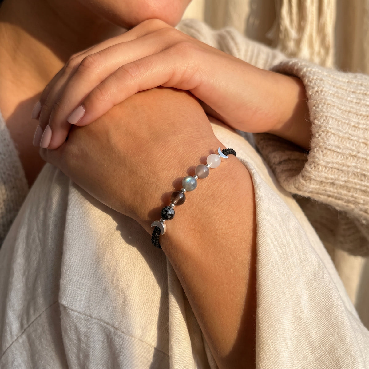 Black moon-phase cord bracelet worn on a wrist