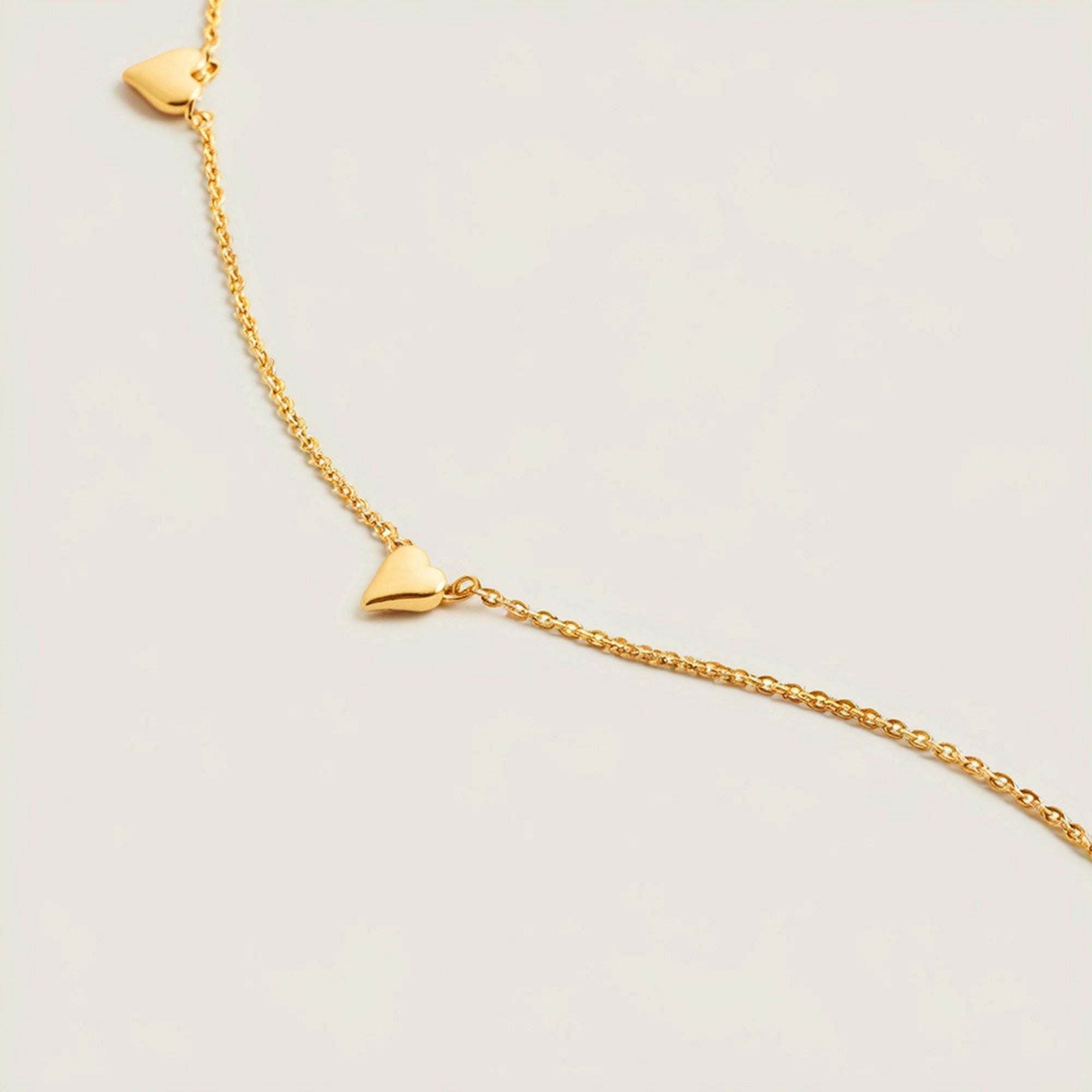Solid gold necklace with spaced 6mm heart charms on an adjustable chain