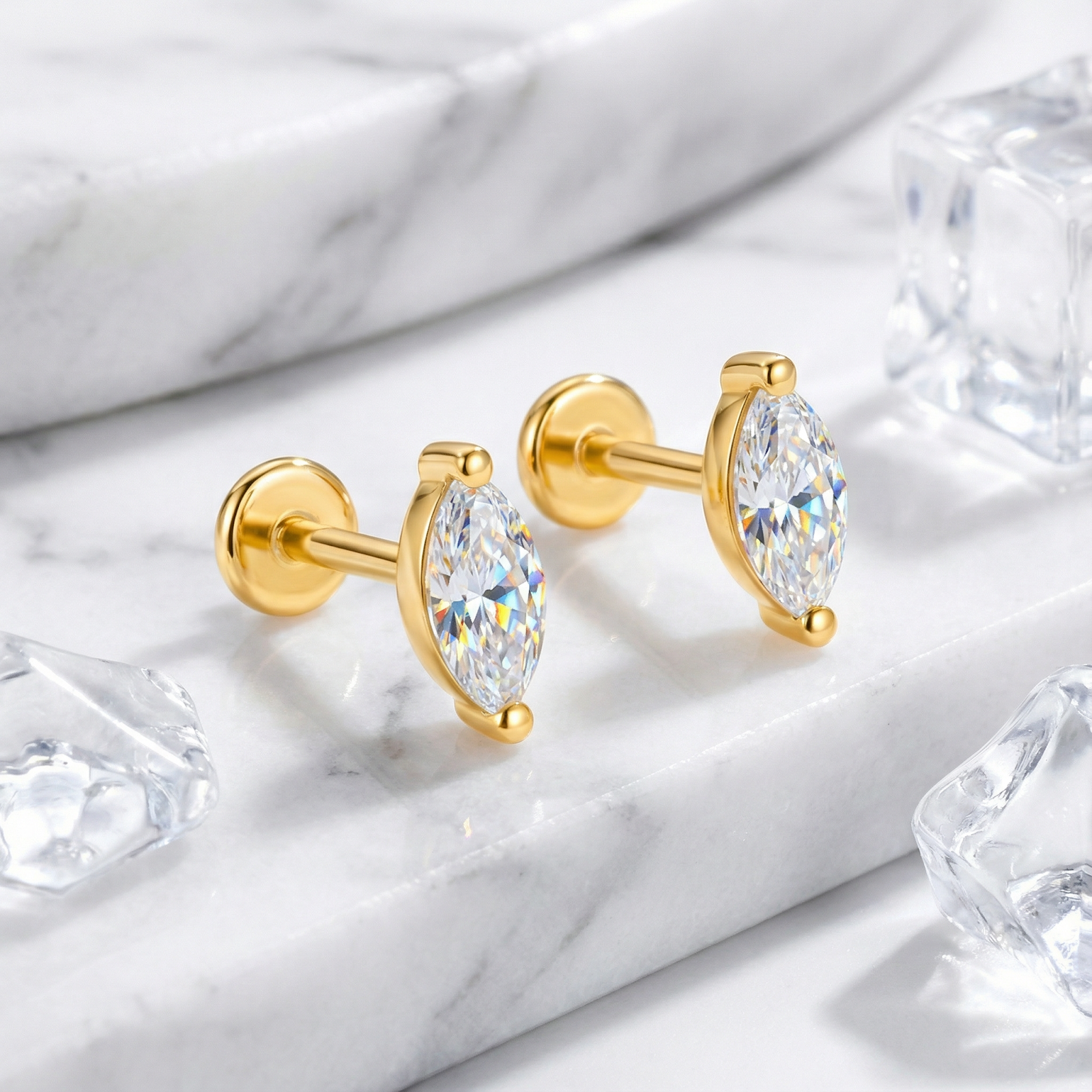 Marquise-cut simulated diamond stud earrings with flat backs in 18K gold vermeil on a marble surface.