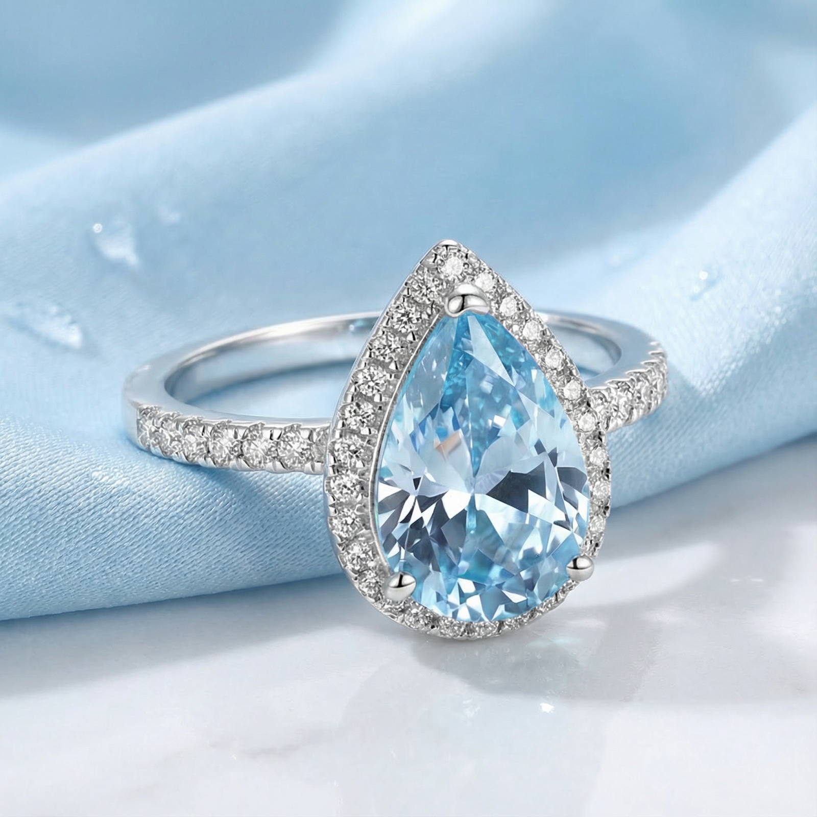Side view of the Alizeh pear halo ring featuring a light blue simulated aquamarine and sterling silver band.