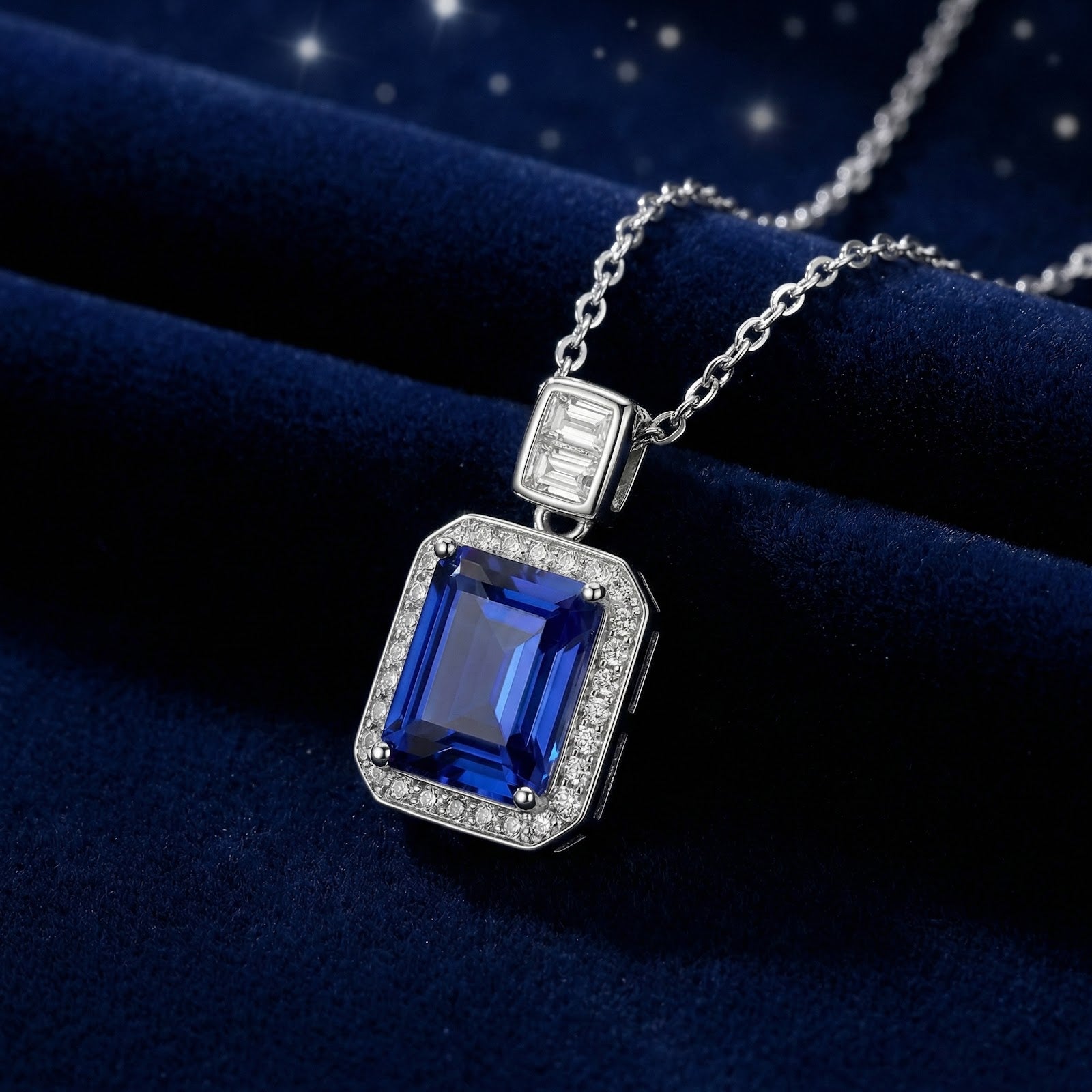 Emerald cut simulated sapphire pendant in sterling silver on a dark blue velvet background.
