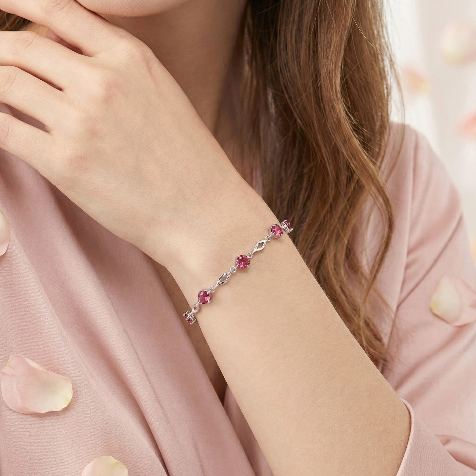 Sterling silver station bracelet with round pink tourmaline stones worn on a woman's wrist.