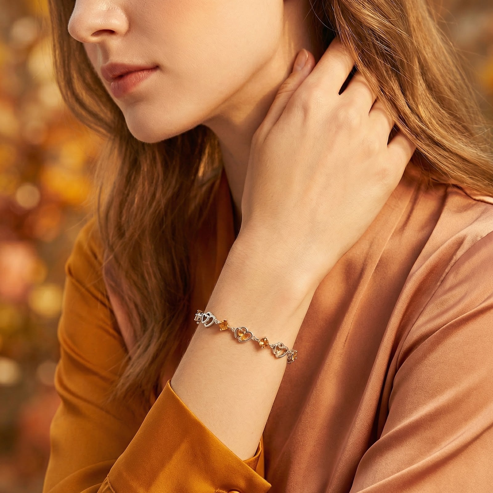 Model wearing the S925 sterling silver Amantelle heart bracelet with golden simulated topaz on her wrist.
