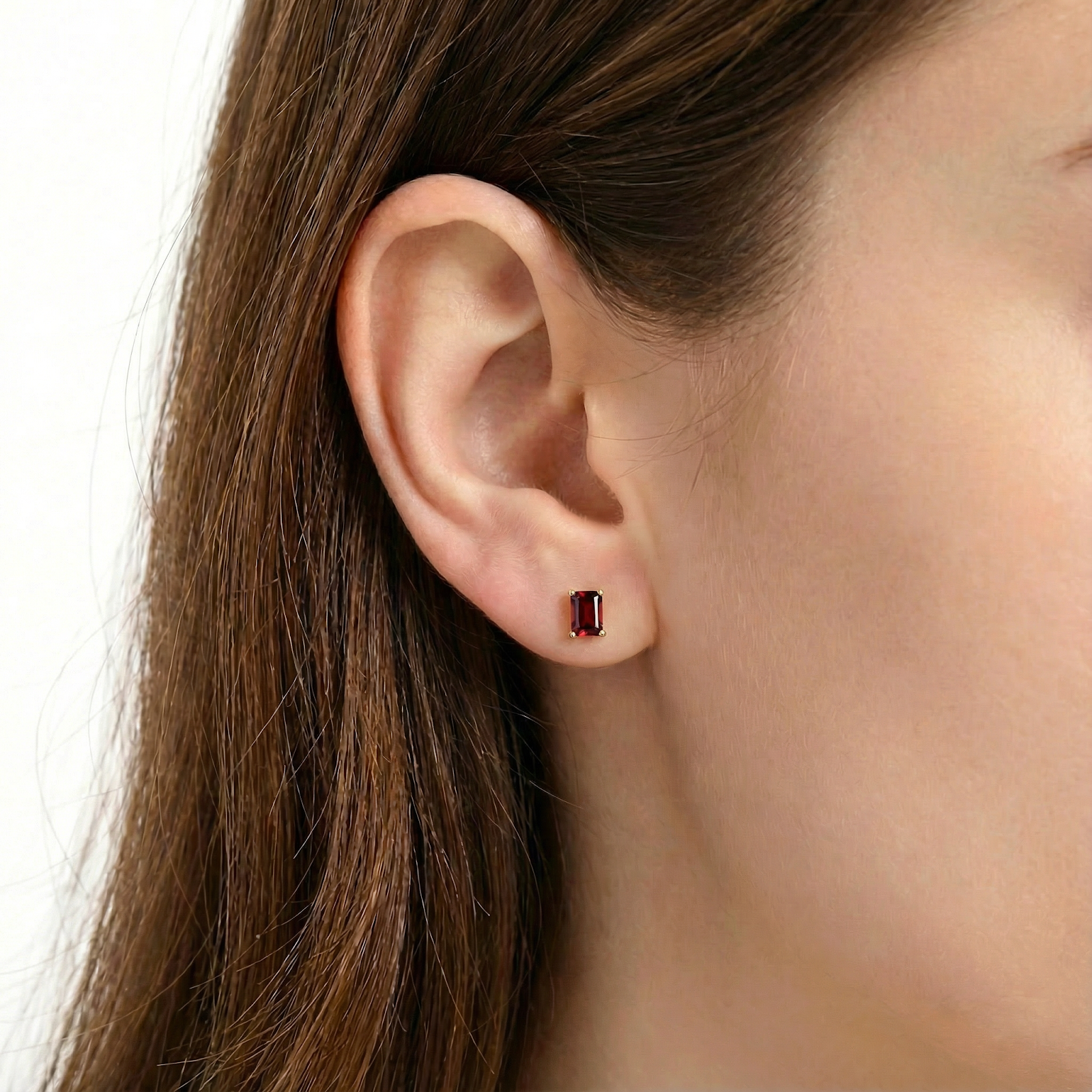 Model wearing a baguette cut simulated garnet stud earring in 18K gold vermeil on her earlobe.