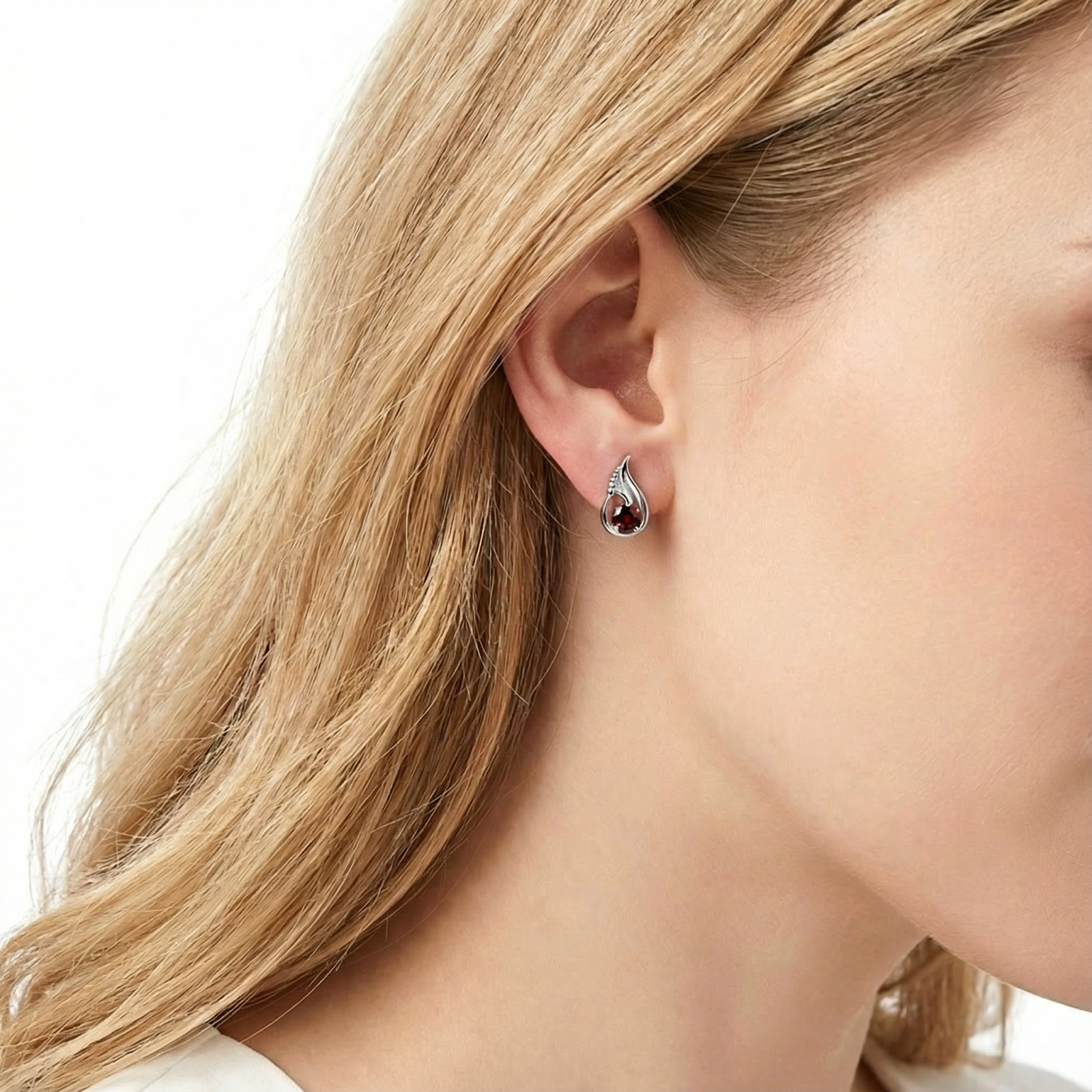 Side view of a woman wearing the sterling silver tulip-shaped earring with a red garnet stone.