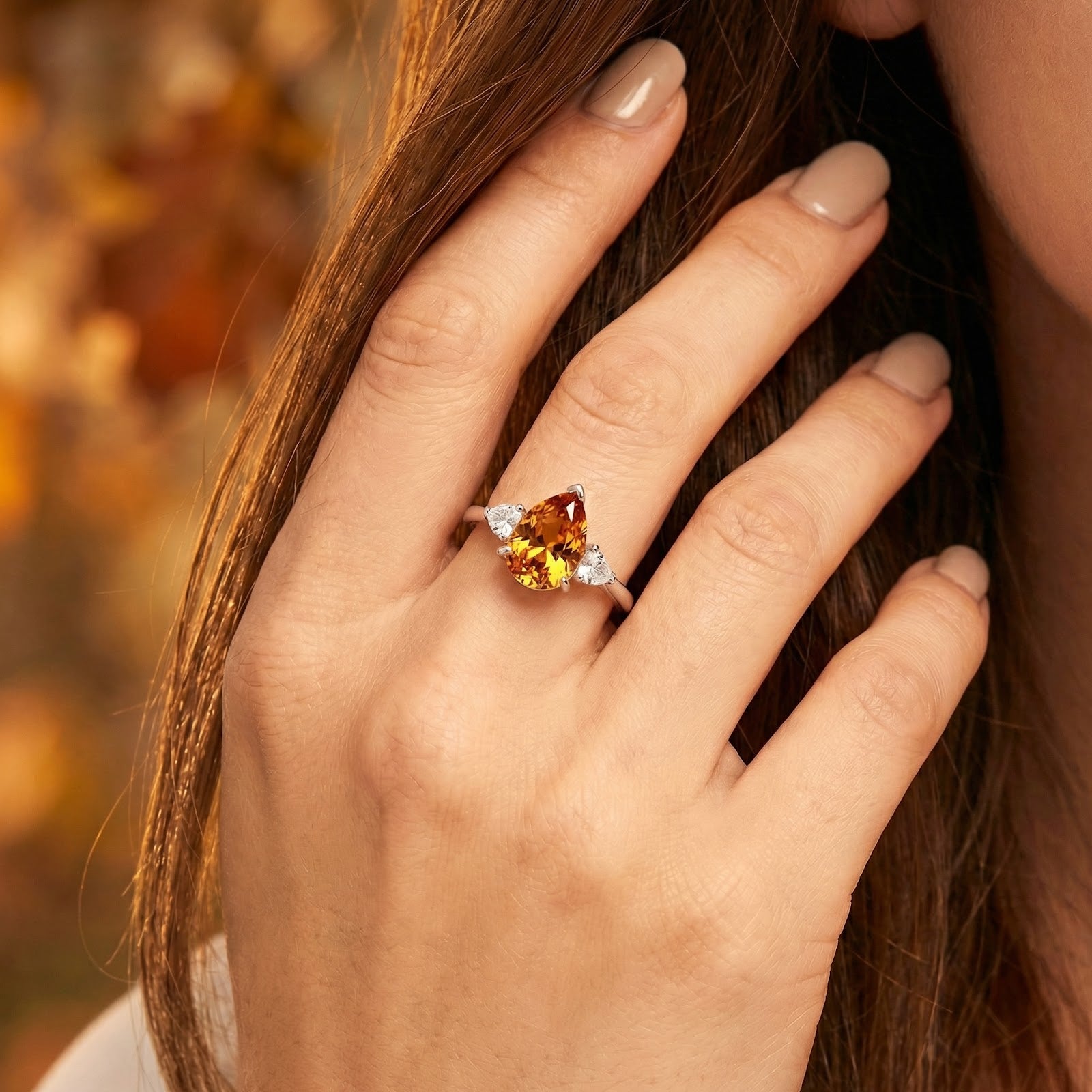 Woman wearing a pear-cut honey simulated topaz ring in silver-tone metal on her ring finger.