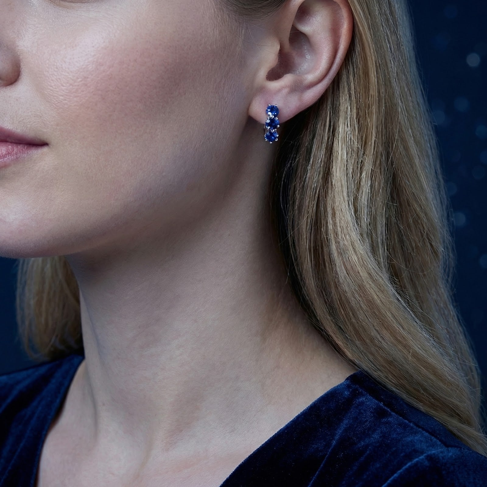 Model wearing the Celestienne sterling silver star huggie earrings with royal blue simulated sapphires.