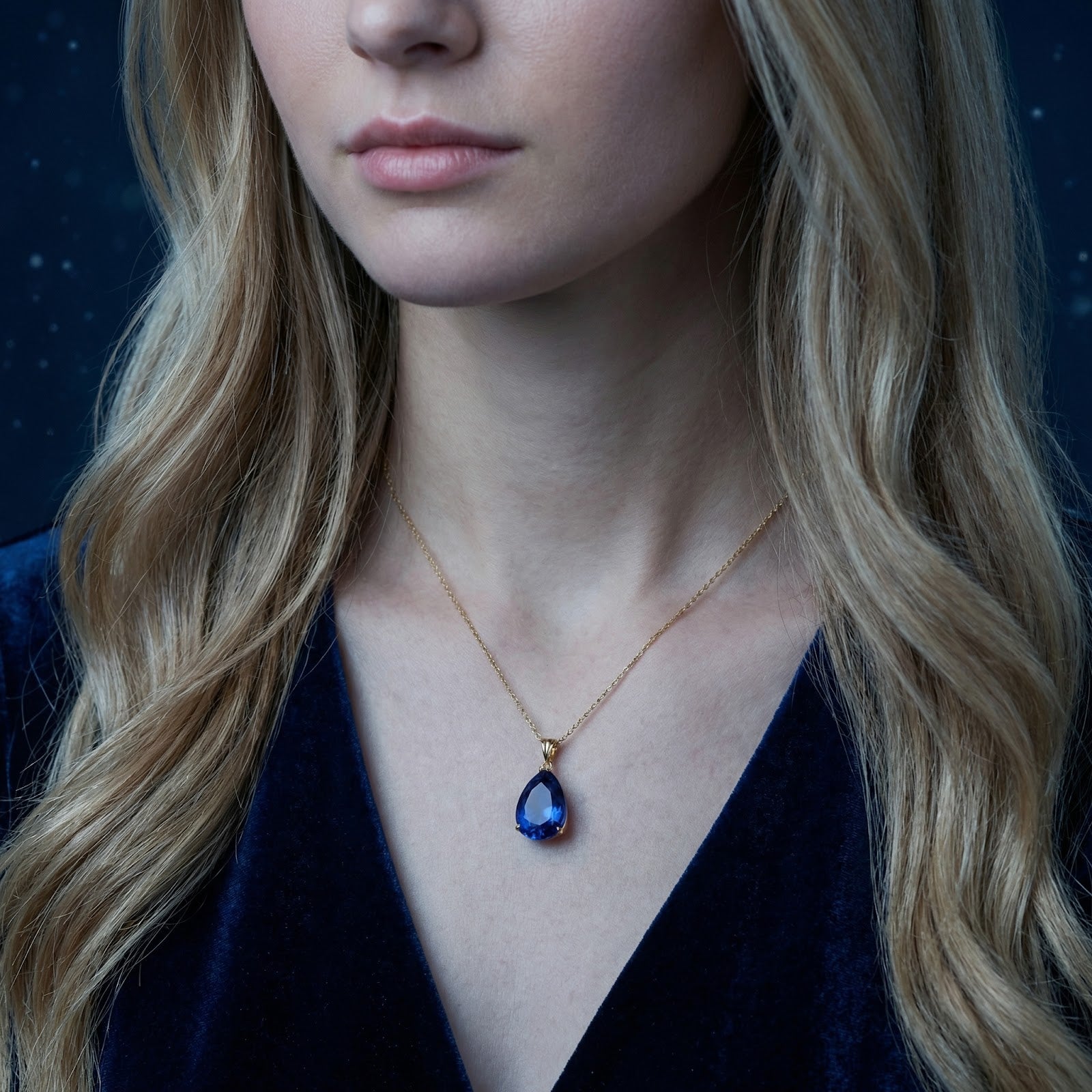Close-up of a woman wearing the pear-cut simulated blue sapphire necklace in 18K gold vermeil.