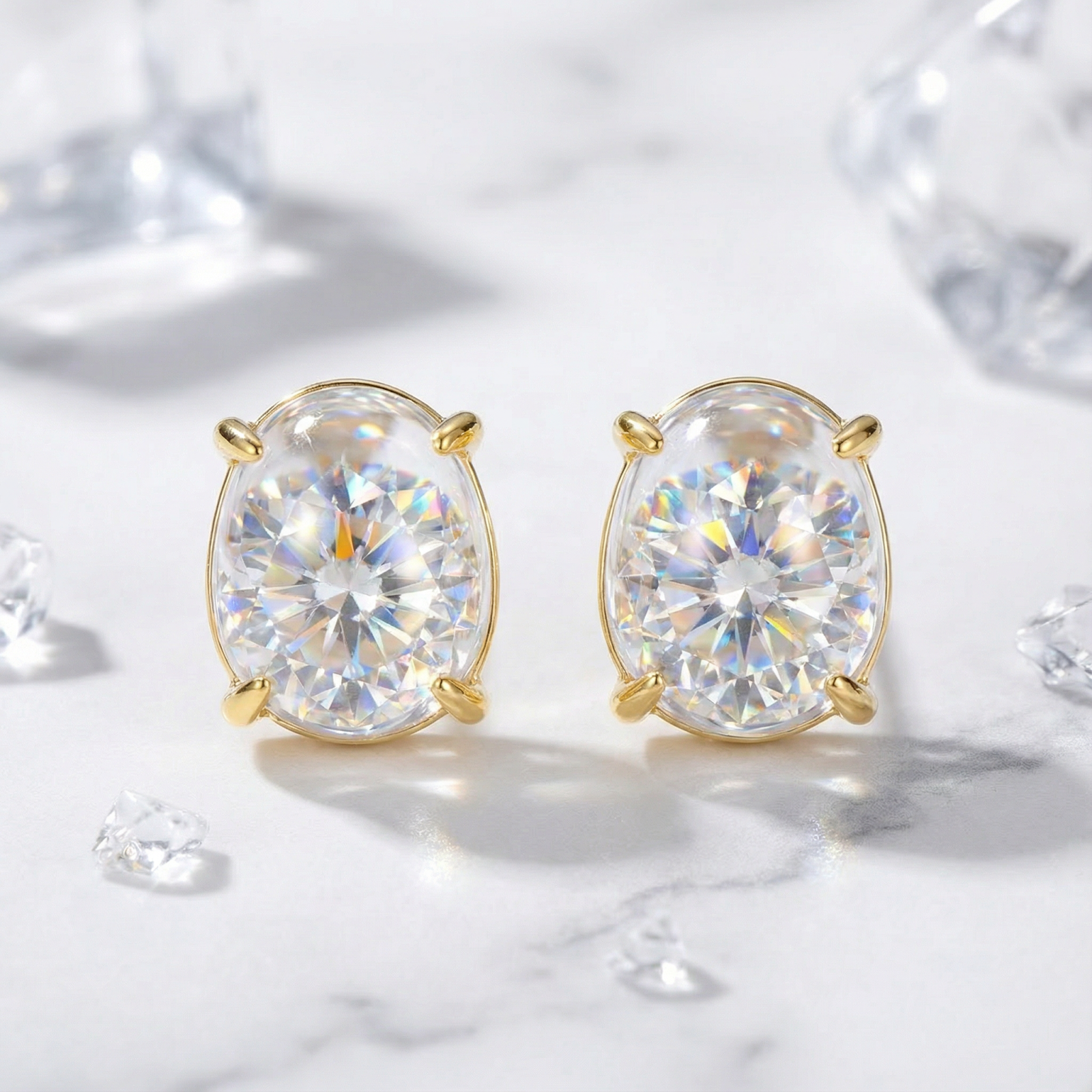 Oval simulated diamond stud earrings in 18K gold vermeil on a marble surface with crystal accents.
