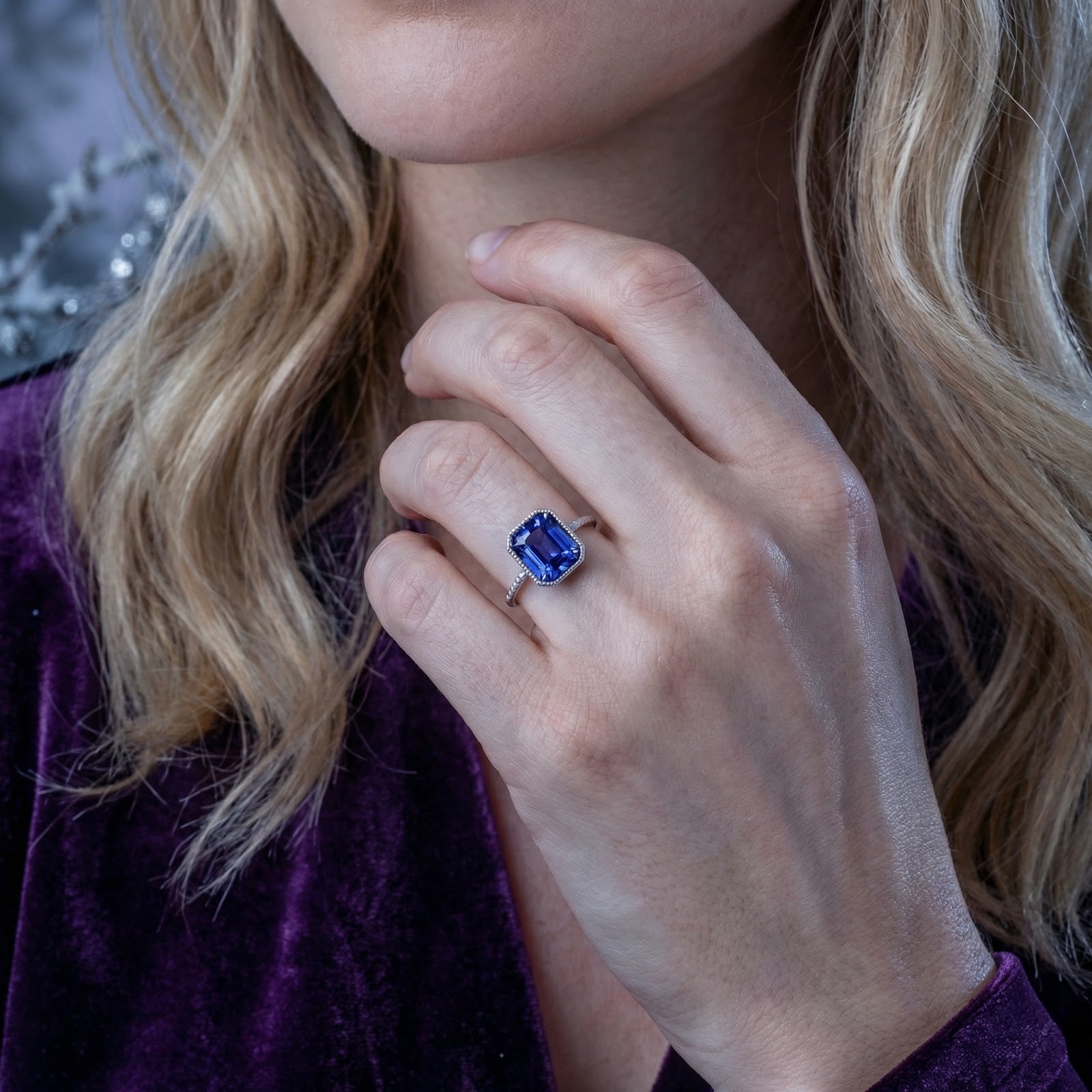 Model wearing the Aurellise silver ring with a square-cut simulated tanzanite and purple velvet top.