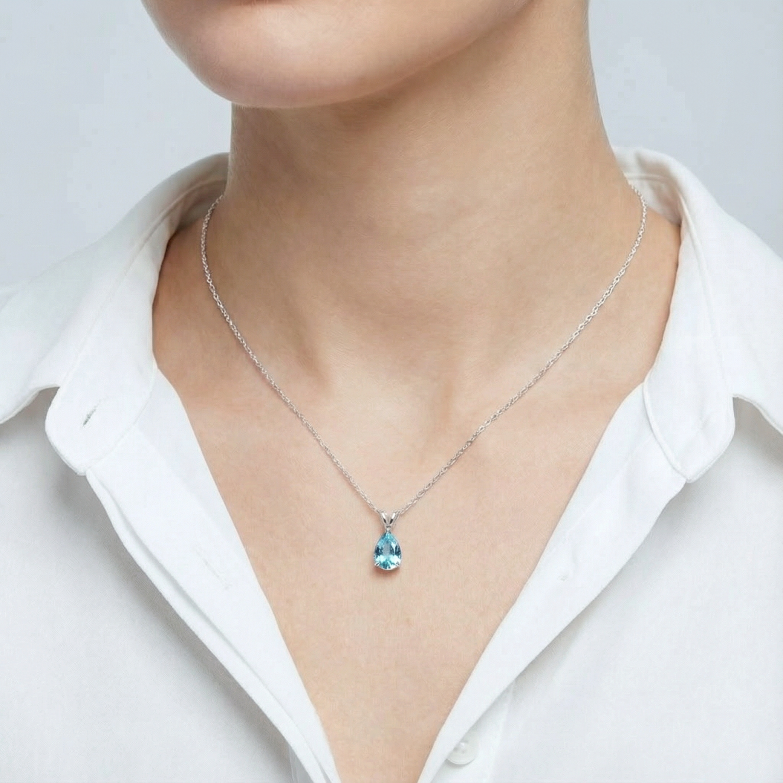 Front view of a model wearing the pear cut simulated aquamarine teardrop necklace in sterling silver.