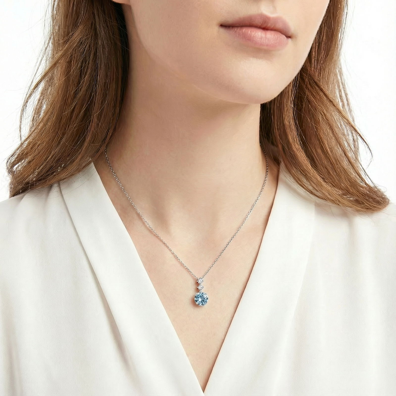 Model wearing the Galene Drop sterling silver necklace with a round-cut light blue simulated aquamarine.