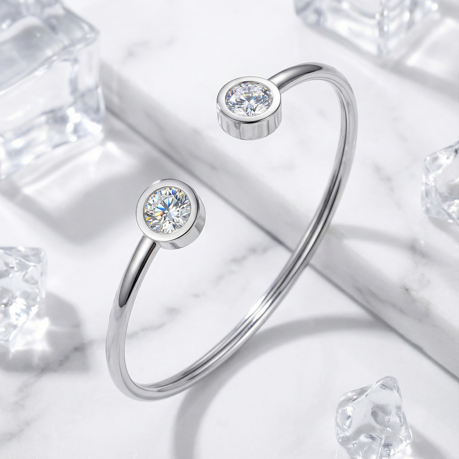 Silver stainless steel cuff bracelet with round-cut simulated diamonds on a marble surface with ice cubes.