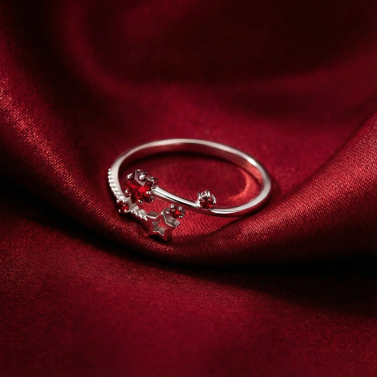 Sterling silver Lyriana star ring featuring a pigeon blood red simulated ruby on a draped red satin background.