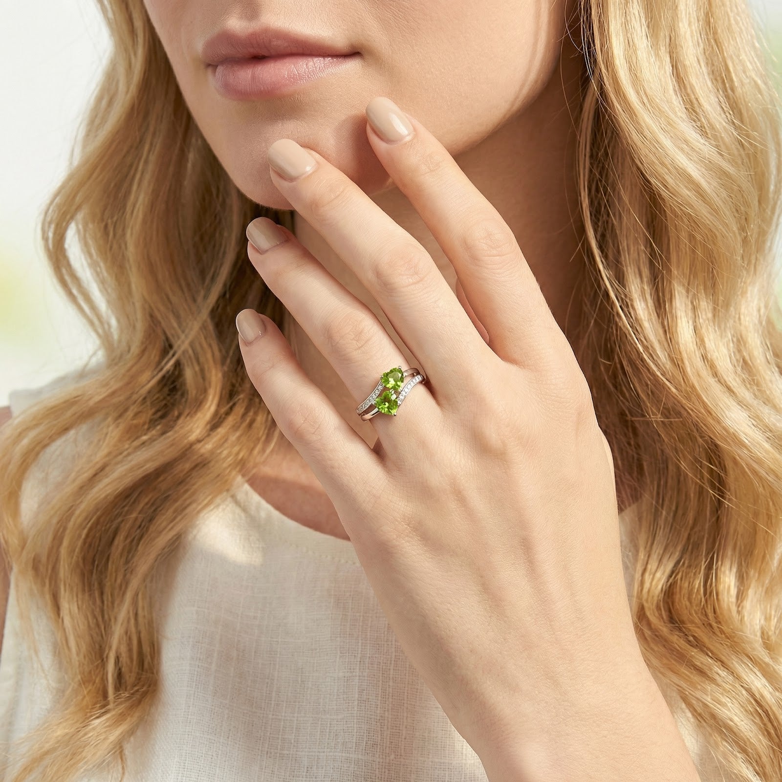 Model wearing the Valisara heart-shaped simulated peridot bypass ring in S925 sterling silver on her ring finger.