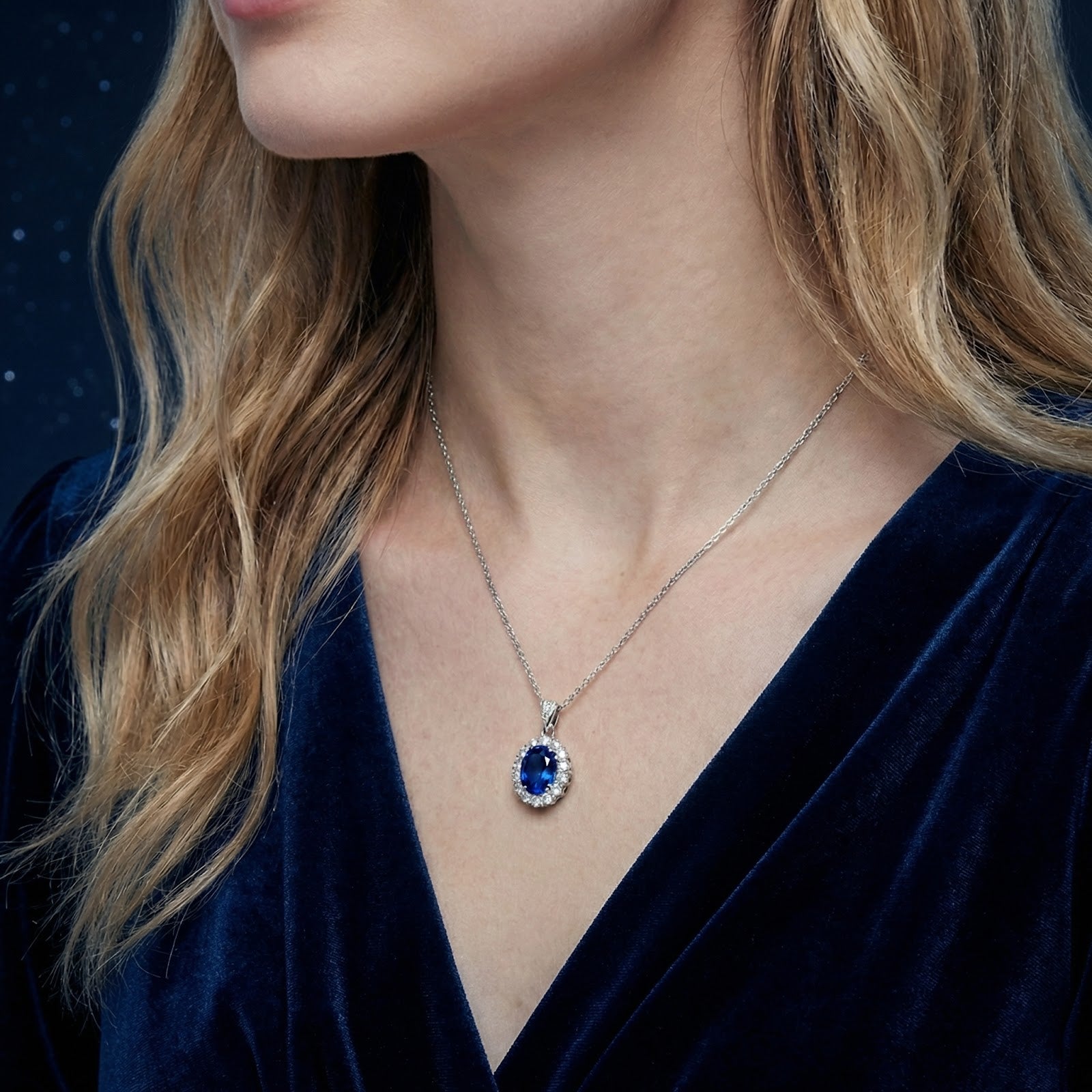 Side profile of a woman wearing the oval-cut blue sapphire halo pendant on a sterling silver chain.