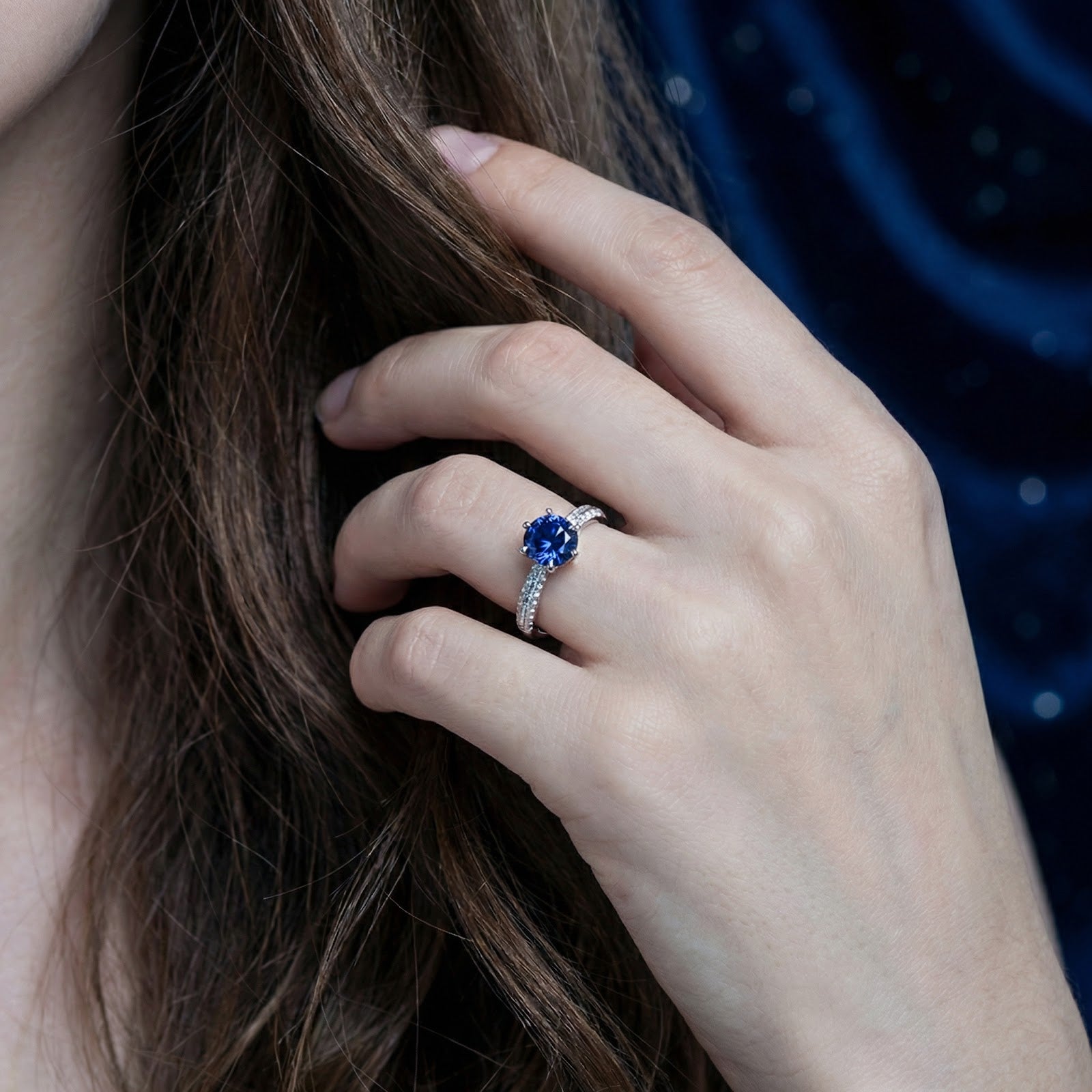 S925 sterling silver solitaire ring with a round blue sapphire shown on a model's hand.