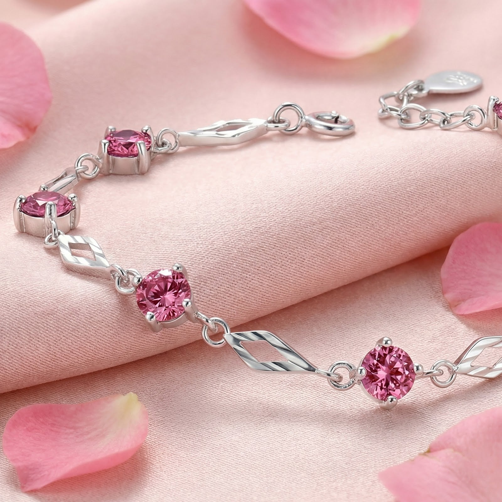 Close-up of round-cut simulated pink tourmaline stones in a sterling silver station bracelet setting.