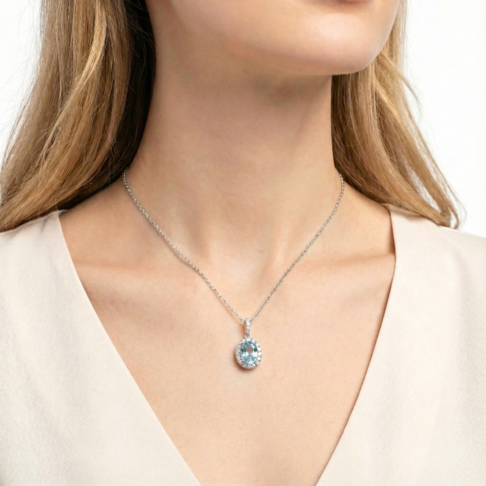 Front view of a woman wearing the March birthstone sterling silver oval simulated aquamarine halo necklace.