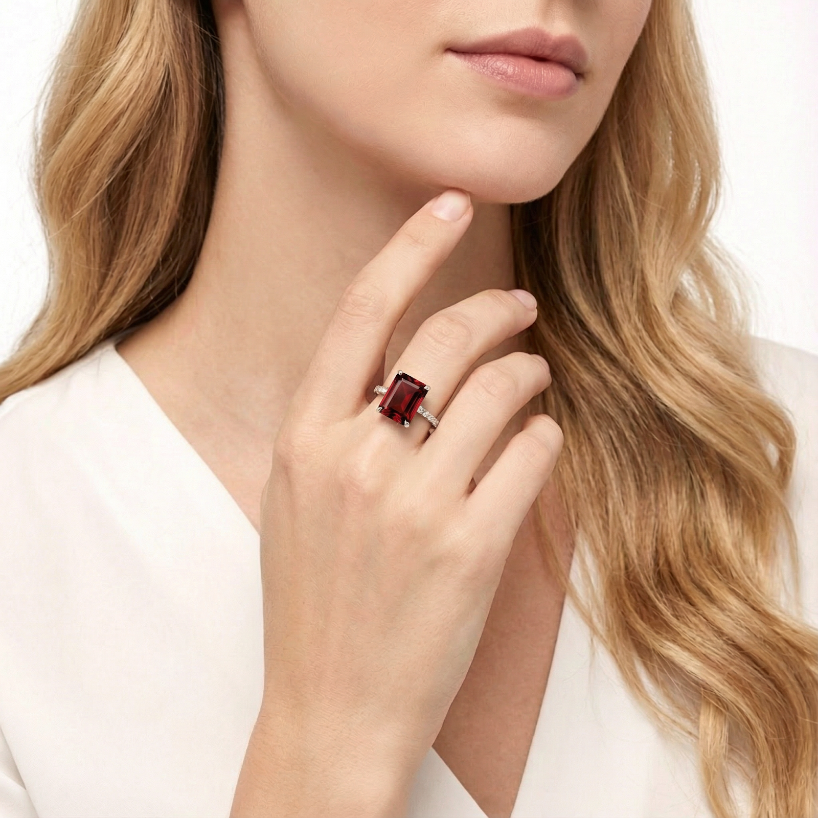 Woman wearing the radiant cut red garnet sterling silver ring on her finger with her hand to her chin.