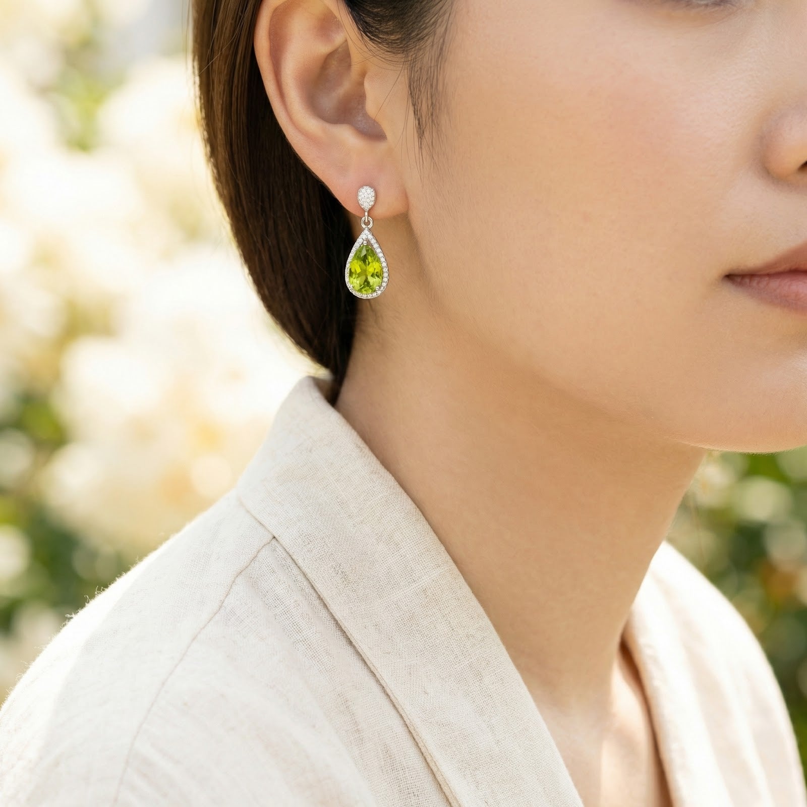 Side view of a woman wearing a Valerelle sterling silver drop earring with a vibrant green simulated peridot.