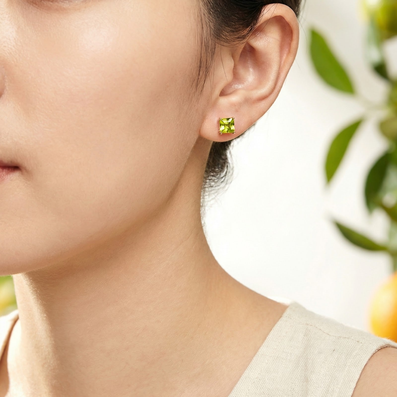 Model wearing a square cut simulated peridot stud earring in 18K rose gold vermeil for size and style reference.