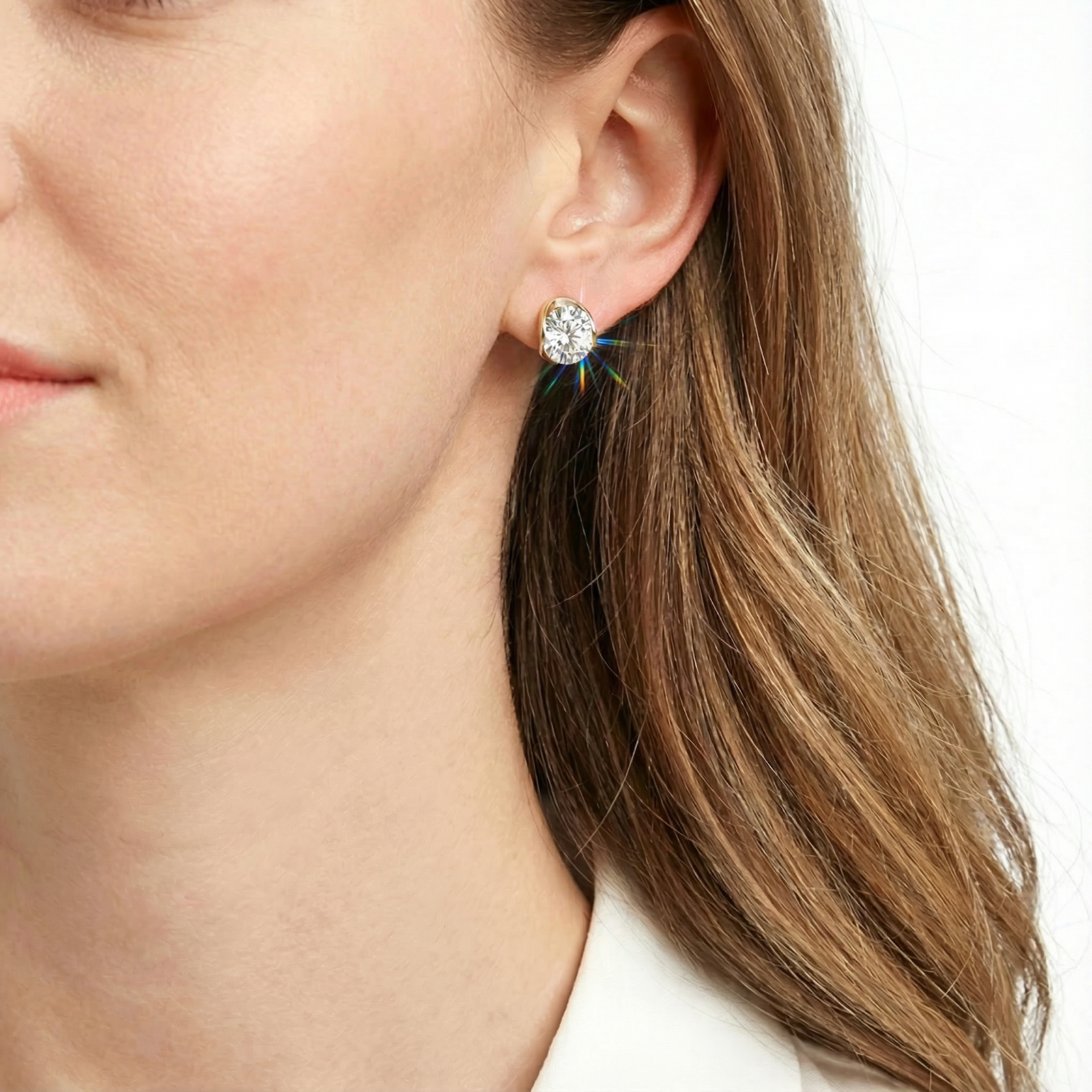 Close-up of a woman wearing the Alysse oval cut zirconia stud earring in 18K gold vermeil.