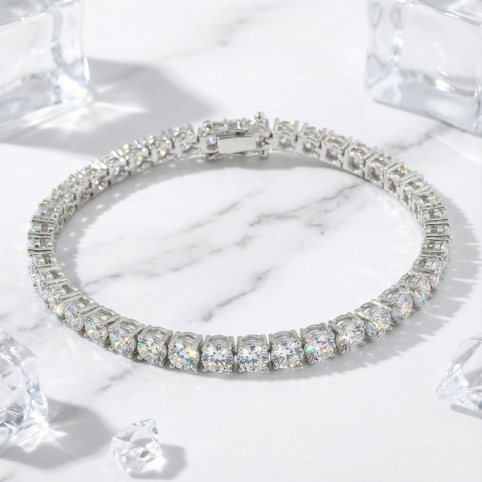 Aris round zirconia tennis bracelet in silver stainless steel on a marble surface with decorative ice cubes.