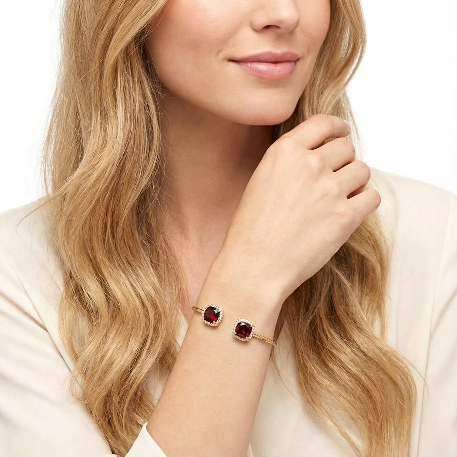 Model wearing a gold cuff bangle with halo-set square cushion-cut simulated garnets on her wrist.
