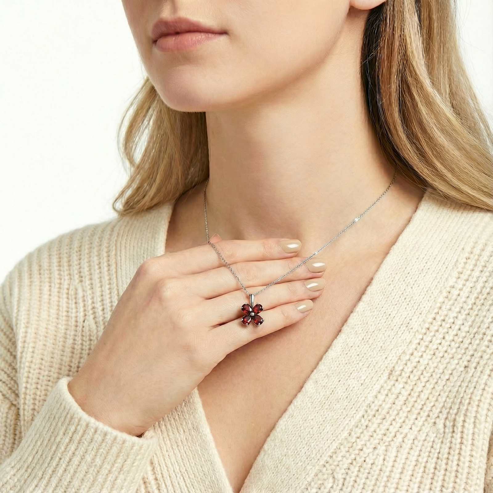 Sterling silver clover necklace with red simulated garnets held by a hand to demonstrate scale and size.