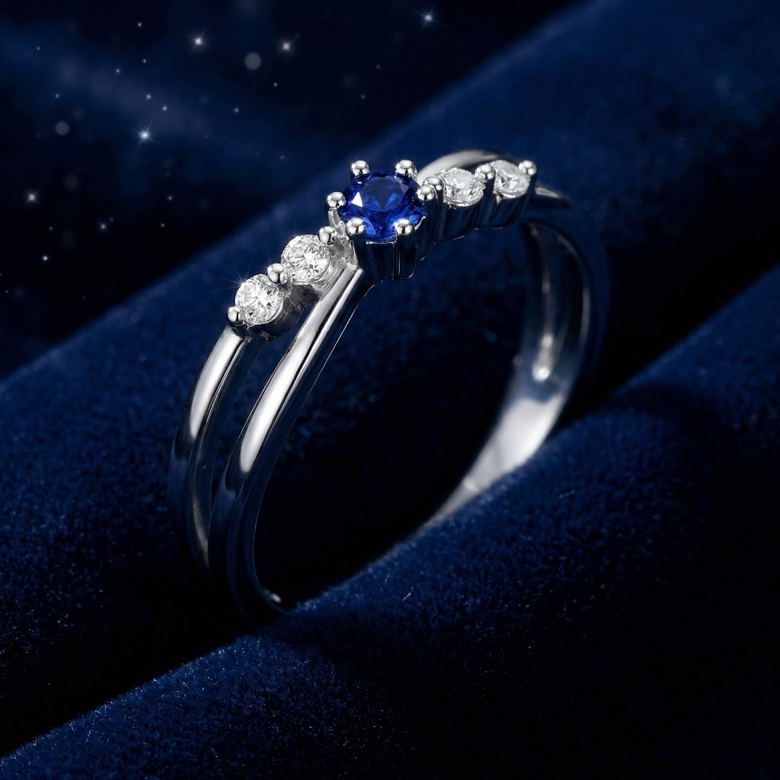Detail view of the Isaraea silver bypass twist ring showing the round blue sapphire and sparkling side stones.