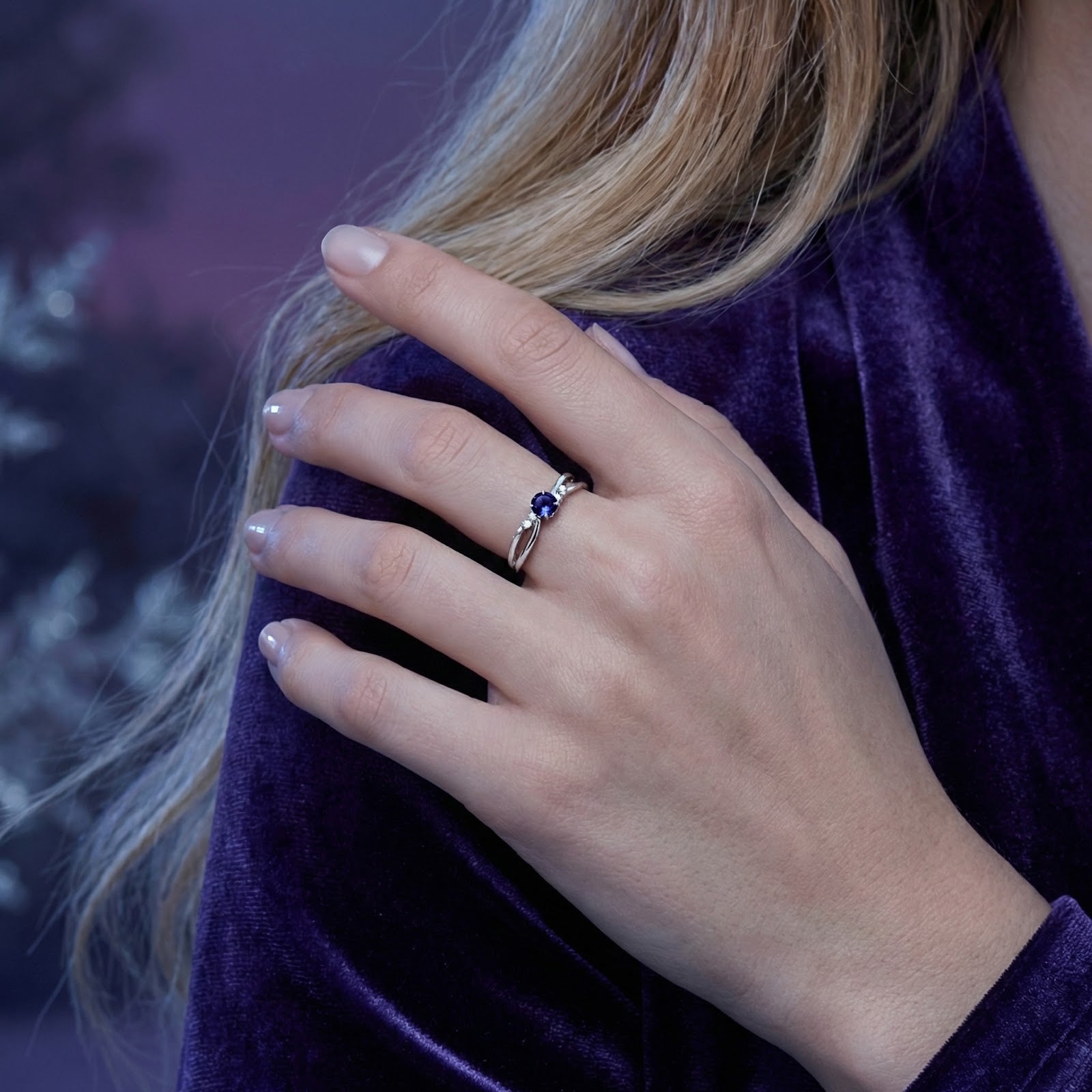S925 sterling silver crossover ring with a blue simulated tanzanite worn on a model's finger.