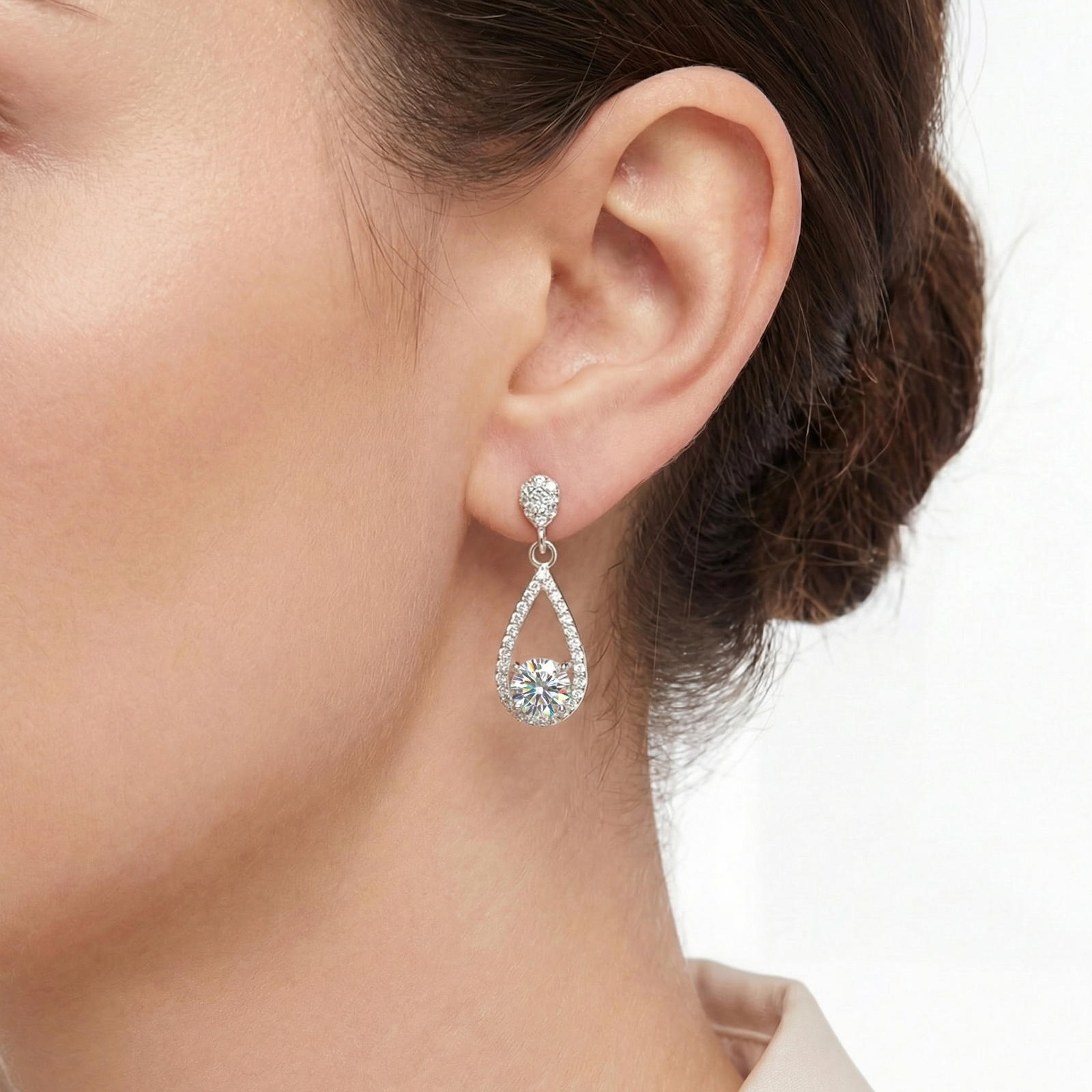 Side view of a woman wearing a silver teardrop drop earring with a round zirconia center stone.