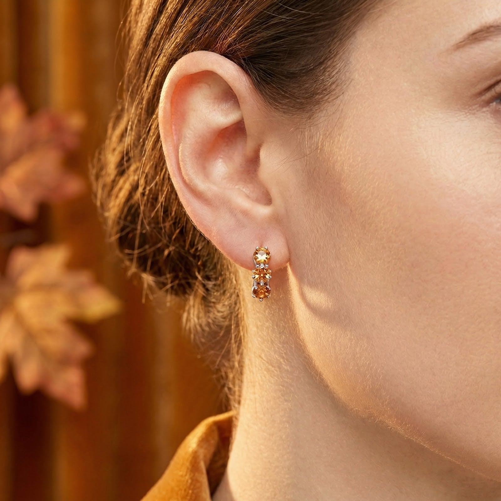 Aurellise sterling silver huggie earring with honeyed simulated topaz stones worn on a woman's ear.