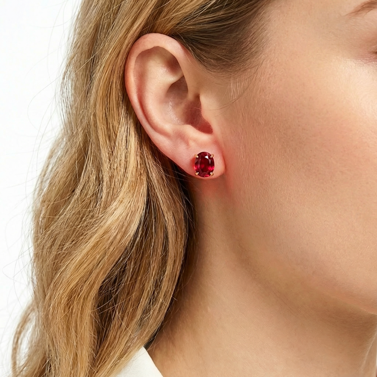 A woman wearing the Rubina stud earring in 18K gold vermeil with a pigeon blood red simulated ruby.