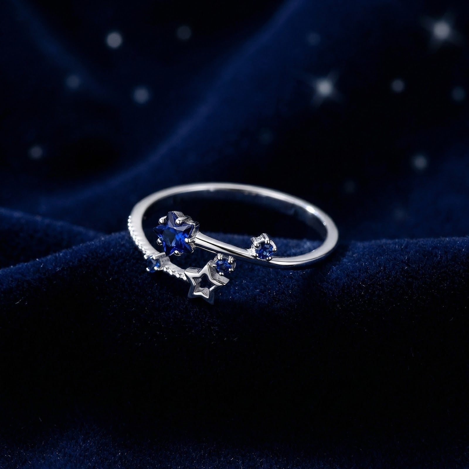 S925 sterling silver Orionis star ring with royal blue simulated sapphires on a navy blue velvet background.