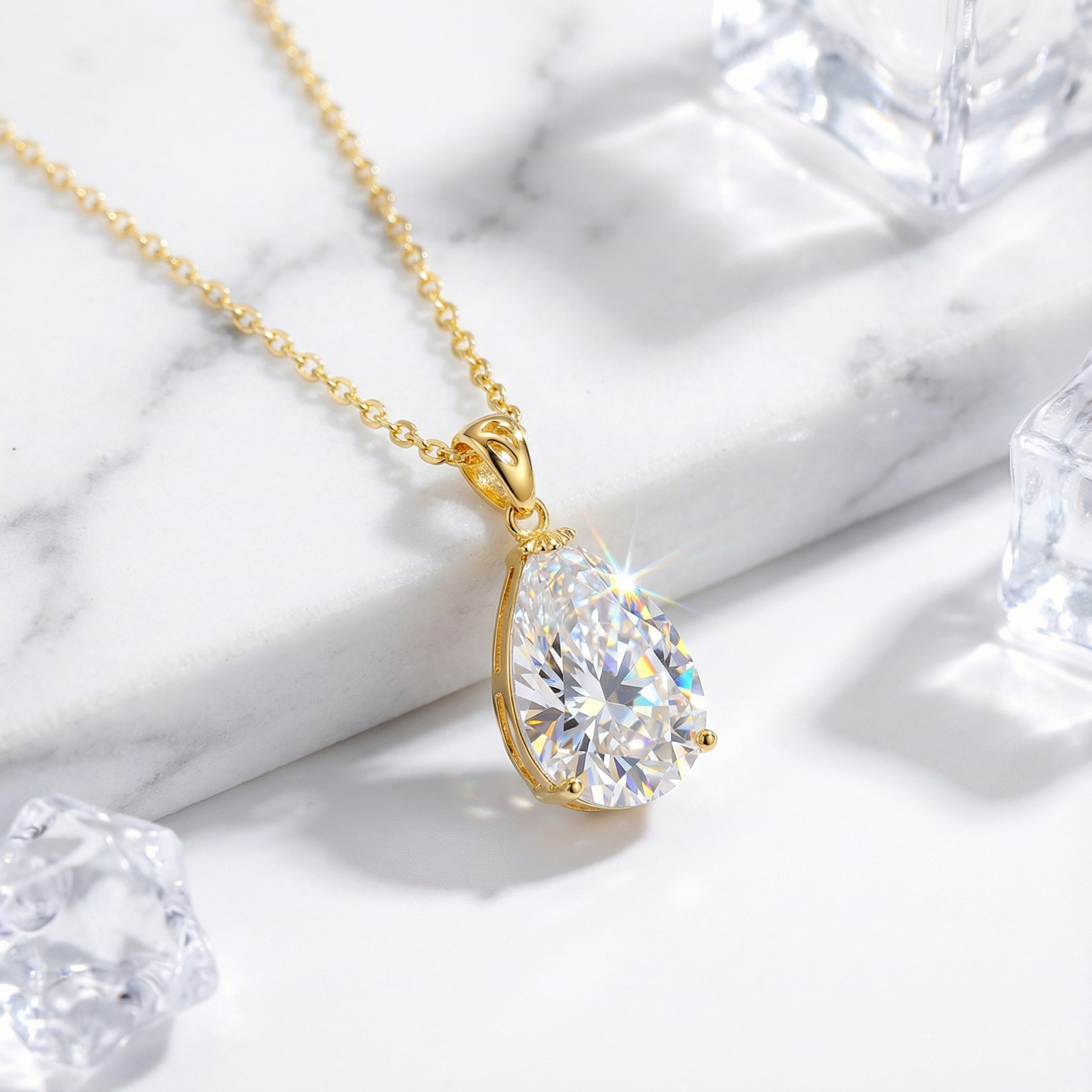 Pear-cut zirconia teardrop pendant on an 18K gold vermeil chain, styled on marble with ice cubes.