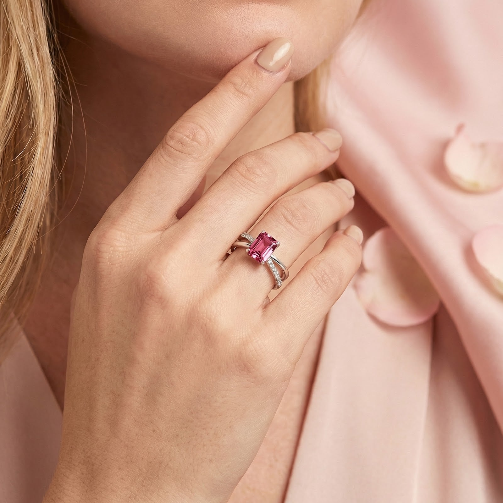 Close-up of the radiant-cut pink tourmaline silver ring worn on a model's hand resting on her chin.