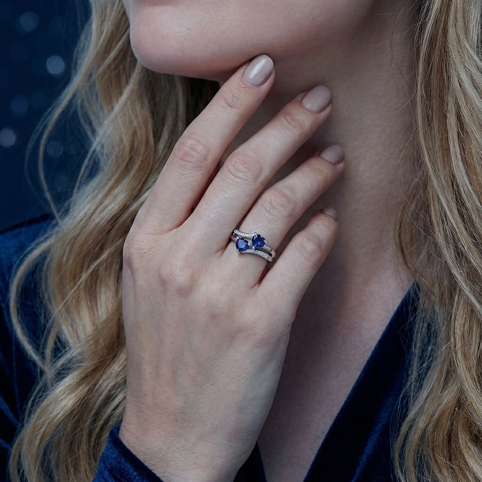 Close-up of a hand wearing the S925 sterling silver bypass ring featuring two heart-cut blue sapphires.