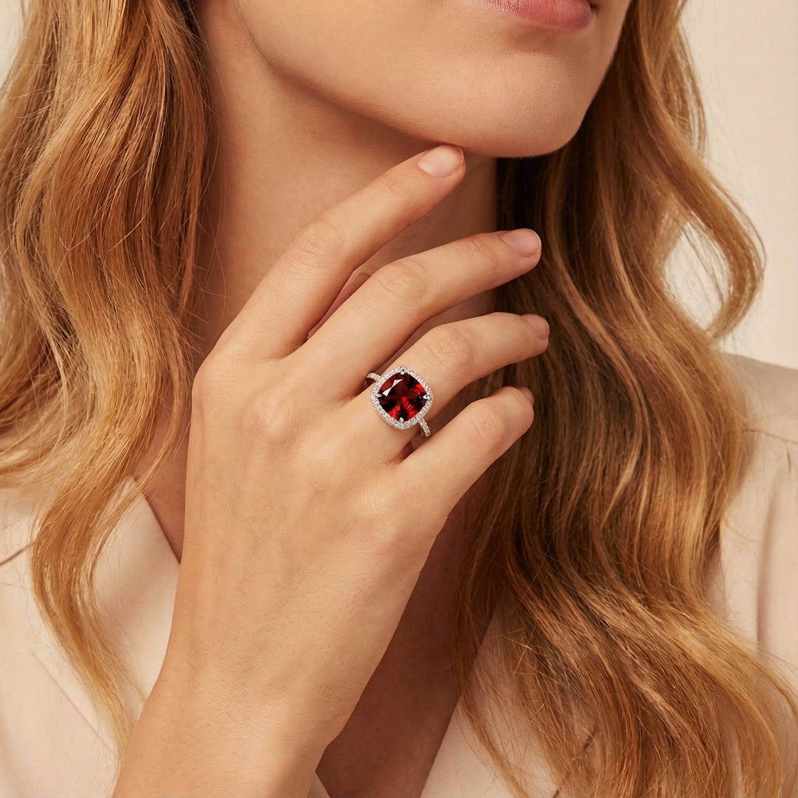 Close-up of a woman's hand wearing the cushion cut red garnet ring in a silver halo setting.
