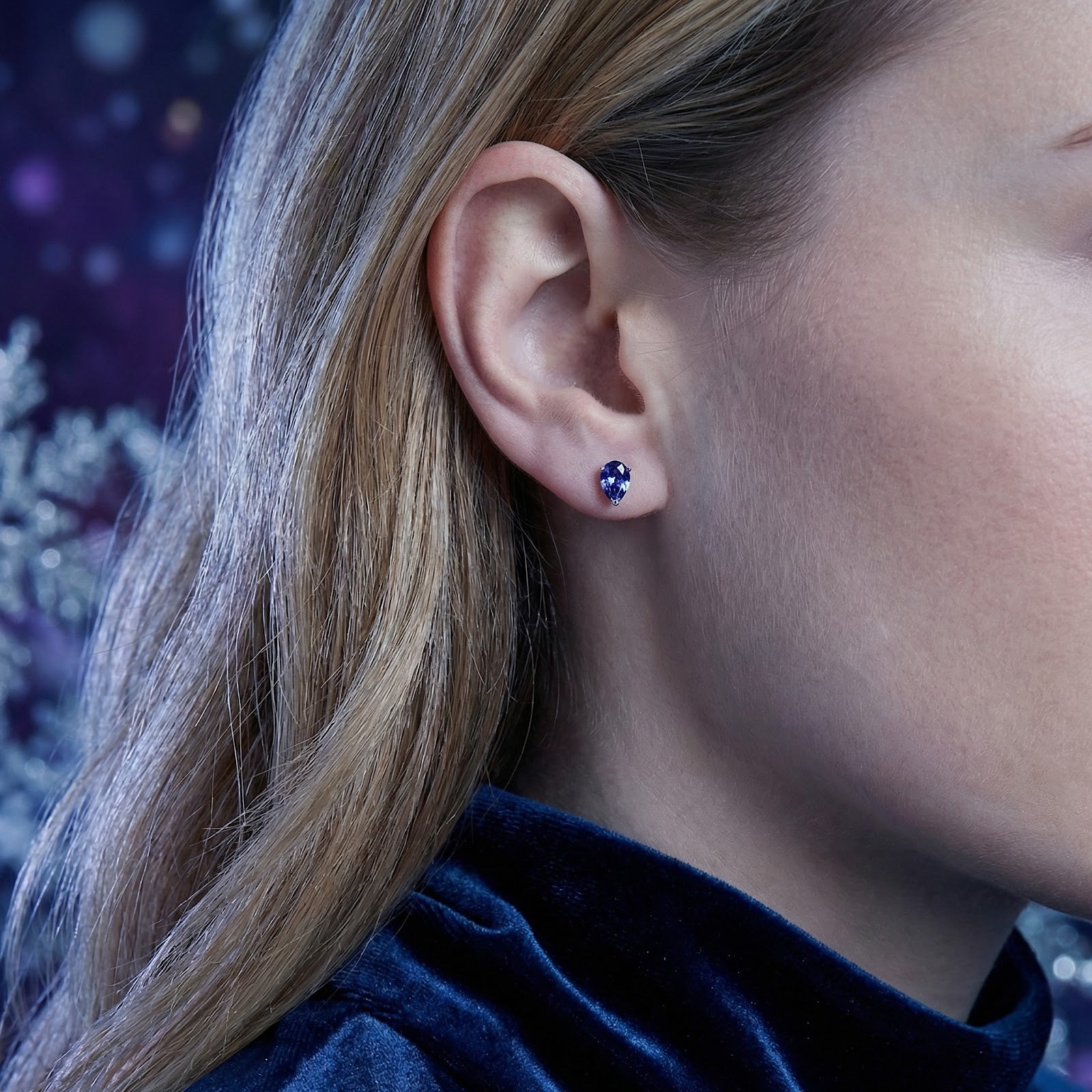 Model wearing a pear-cut simulated tanzanite stud earring in 18K gold vermeil on her ear.