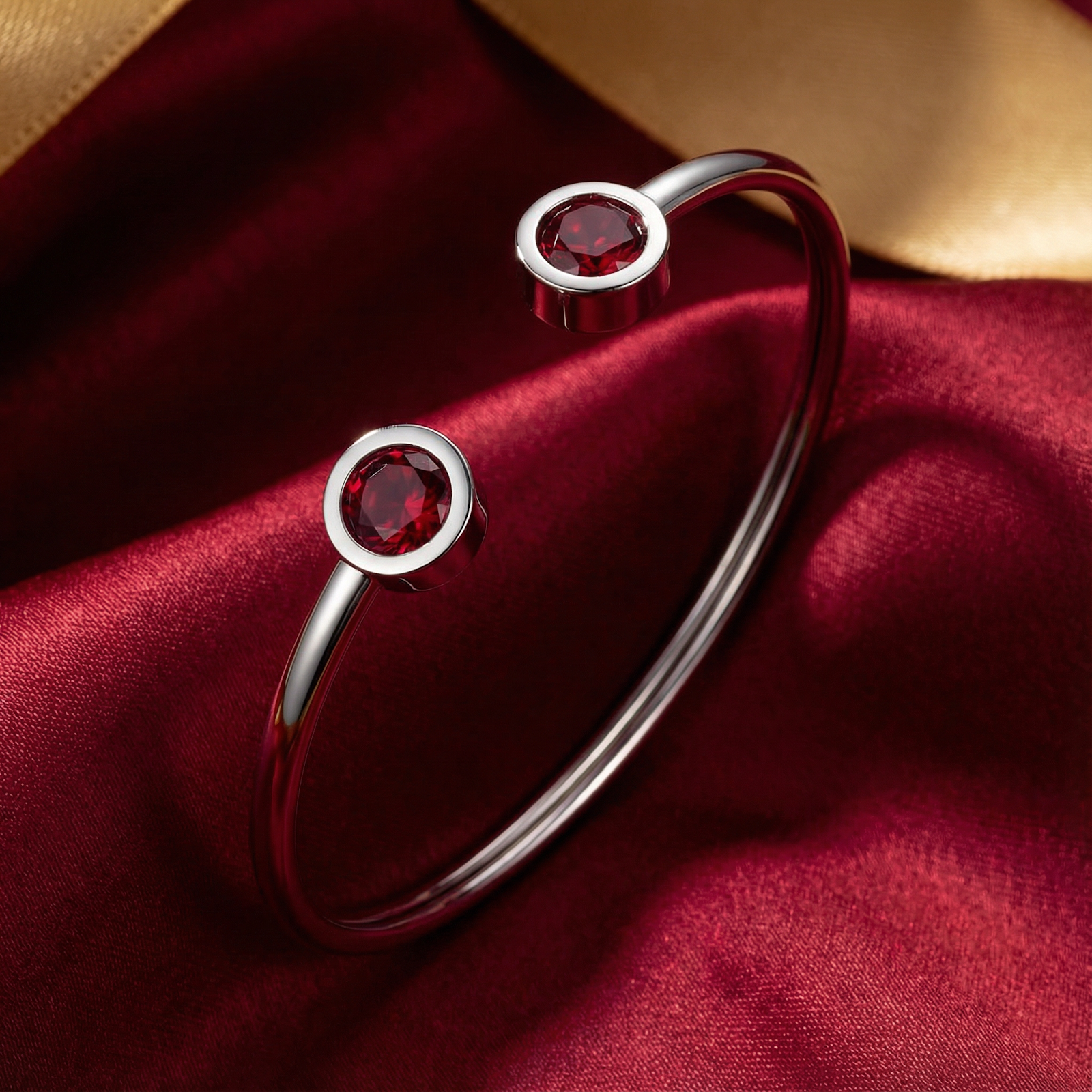 Silver stainless steel Selenis bangle with round red simulated rubies on a red satin background.