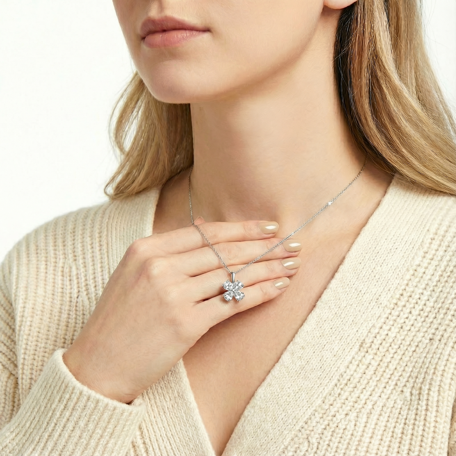 Sterling silver clover necklace held against the neck to show the scale of the pear-cut zirconia pendant.