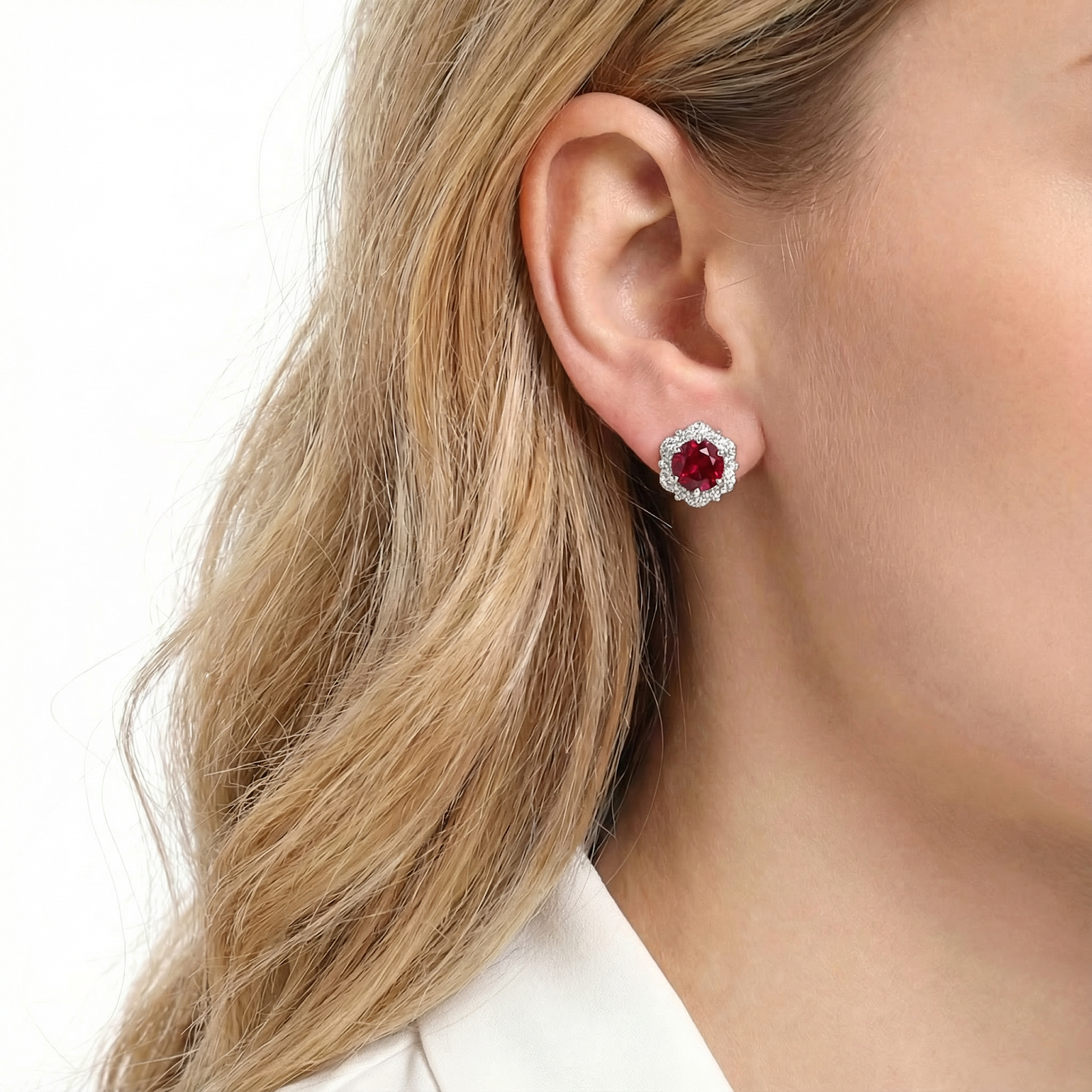 Model wearing a round-cut simulated ruby halo stud earring in rhodium-plated sterling silver.